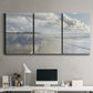 Three-panel canvas wall art featuring endless beach meeting ocean horizon, displayed above a desk in a home office.