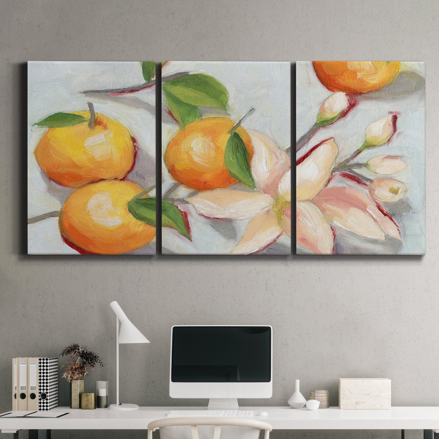 Three-panel canvas wall art featuring bright tangerine still life blossoms, displayed above a desk in a home office.
