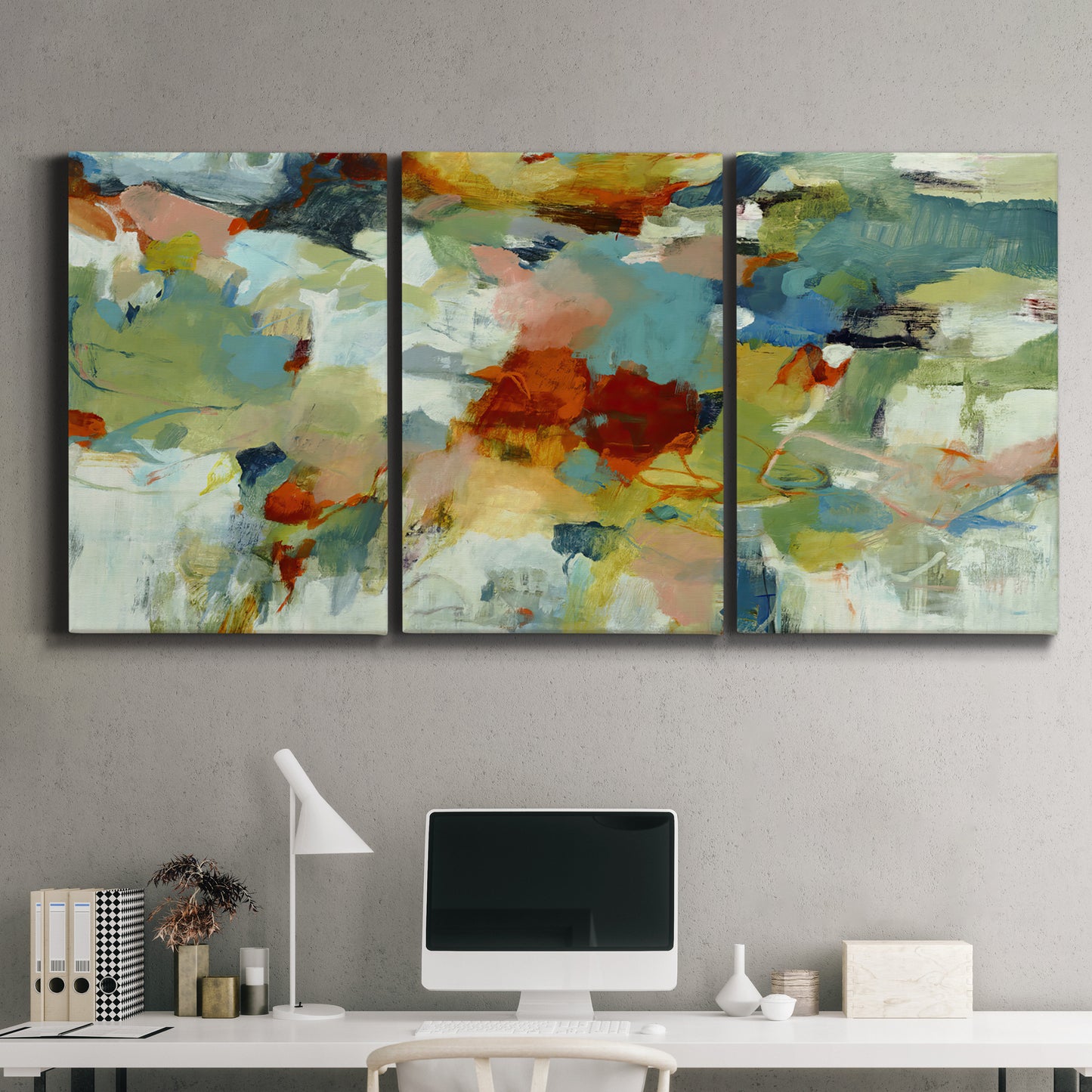 Three-panel canvas wall art featuring celebratory abstract color movement, displayed above a desk in a home office.