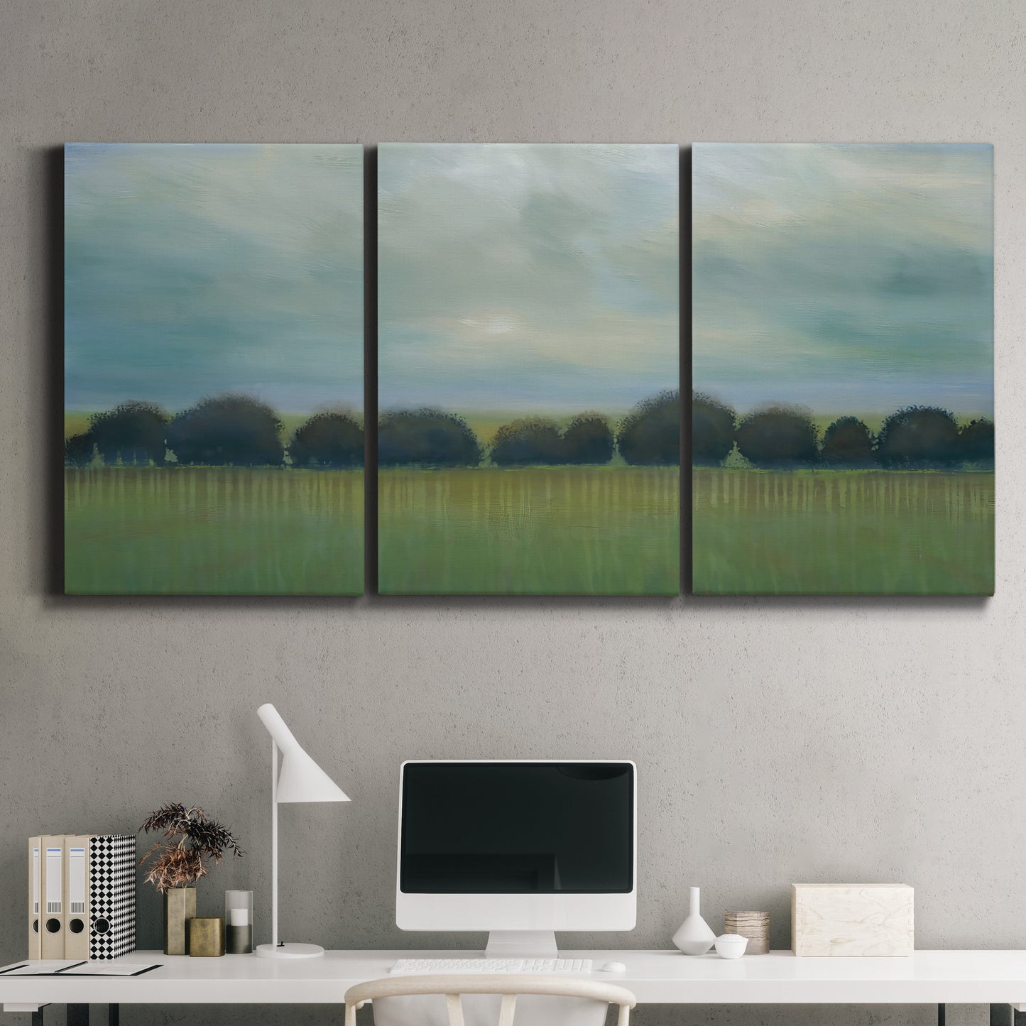 Three-panel canvas wall art featuring rolling green pastoral fields, displayed above a desk in a home office.