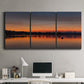 Three-panel canvas wall art featuring glowing sunset over water, displayed above a desk in a home office.