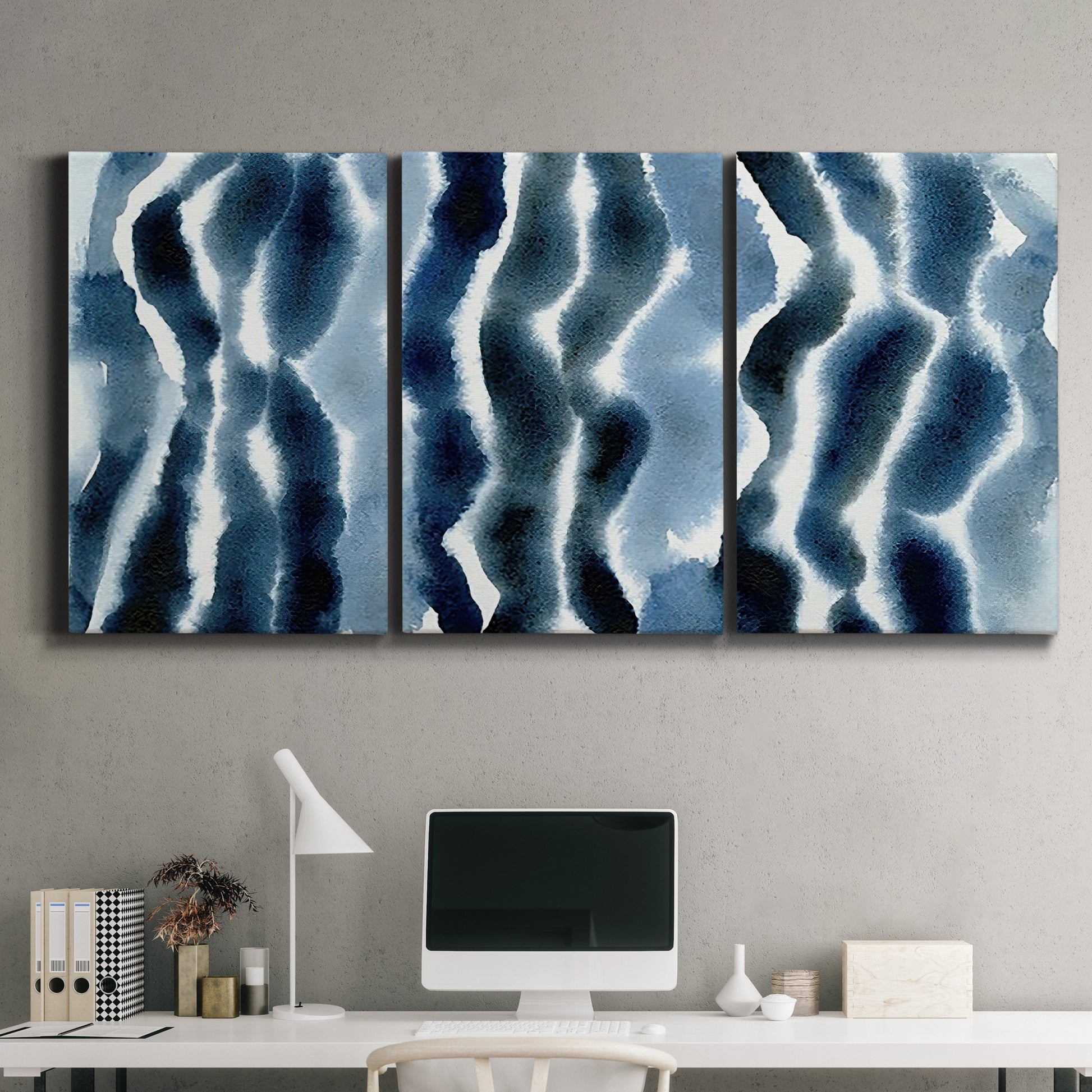 Three-panel canvas wall art featuring flowing blue watercolor wave forms, displayed above a desk in a home office.