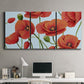 Three-panel canvas wall art featuring red poppies in motion, displayed above a desk in a home office.