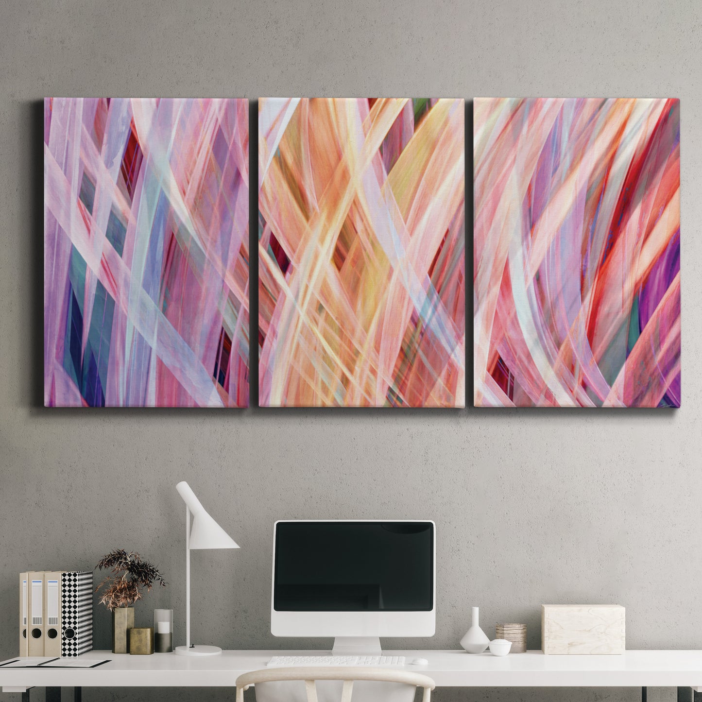 Three-panel canvas wall art featuring layered modern abstract color ribbons, displayed above a desk in a home office.