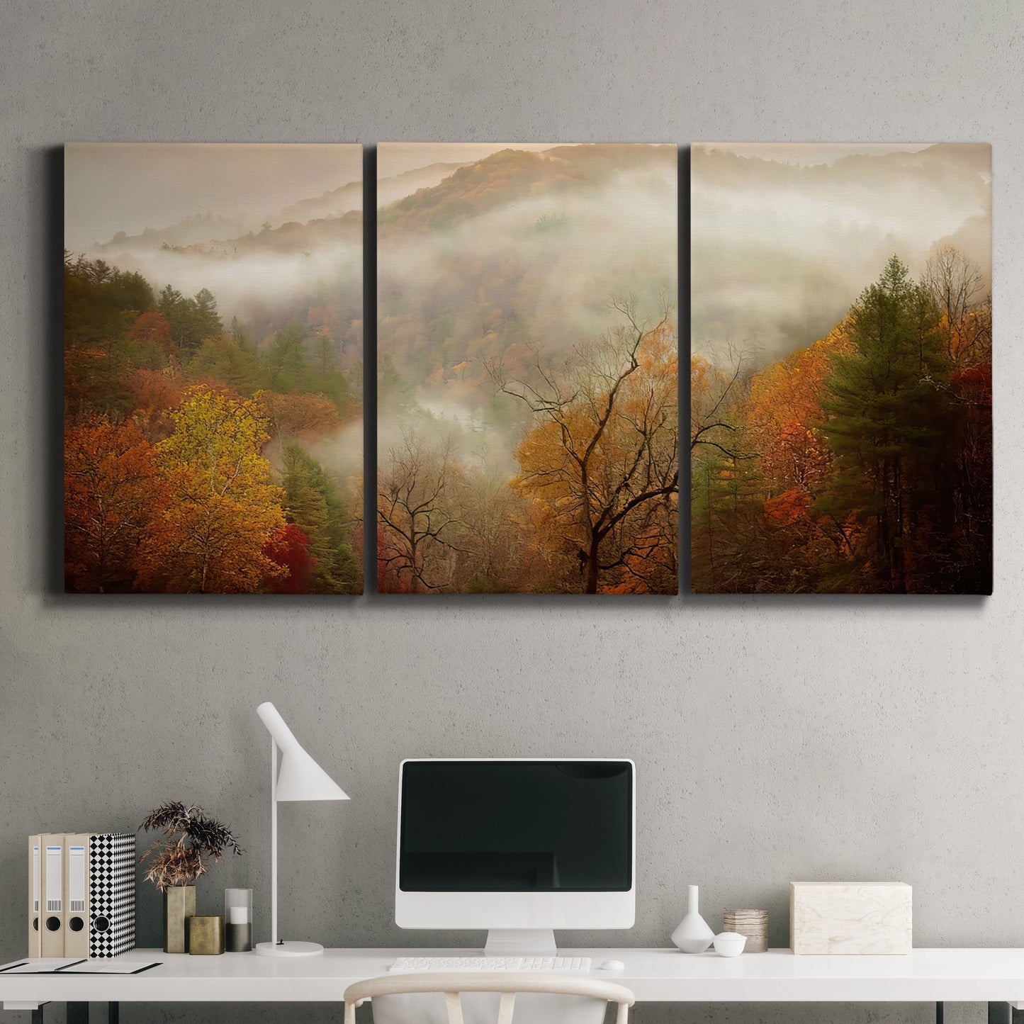 Three-panel canvas wall art featuring misty autumn landscape photograph, displayed above a desk in a home office.