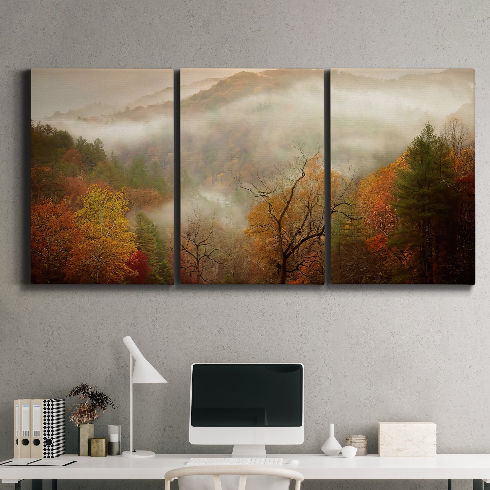 Three-panel canvas wall art featuring misty autumn landscape photograph, displayed above a desk in a home office.