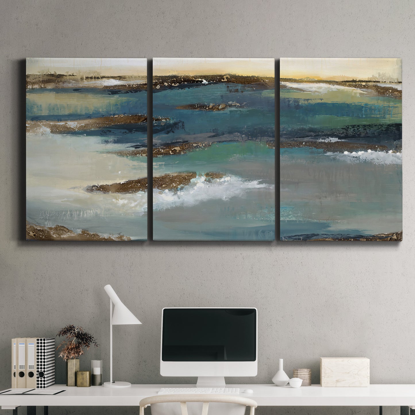 Three-panel canvas wall art featuring rocky coastal bluff above sea, displayed above a desk in a home office.