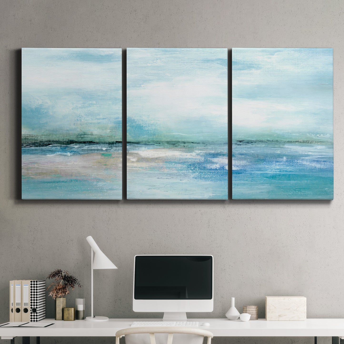 Three-panel canvas wall art featuring sunset silhouette over coastal water, displayed above a desk in a home office.