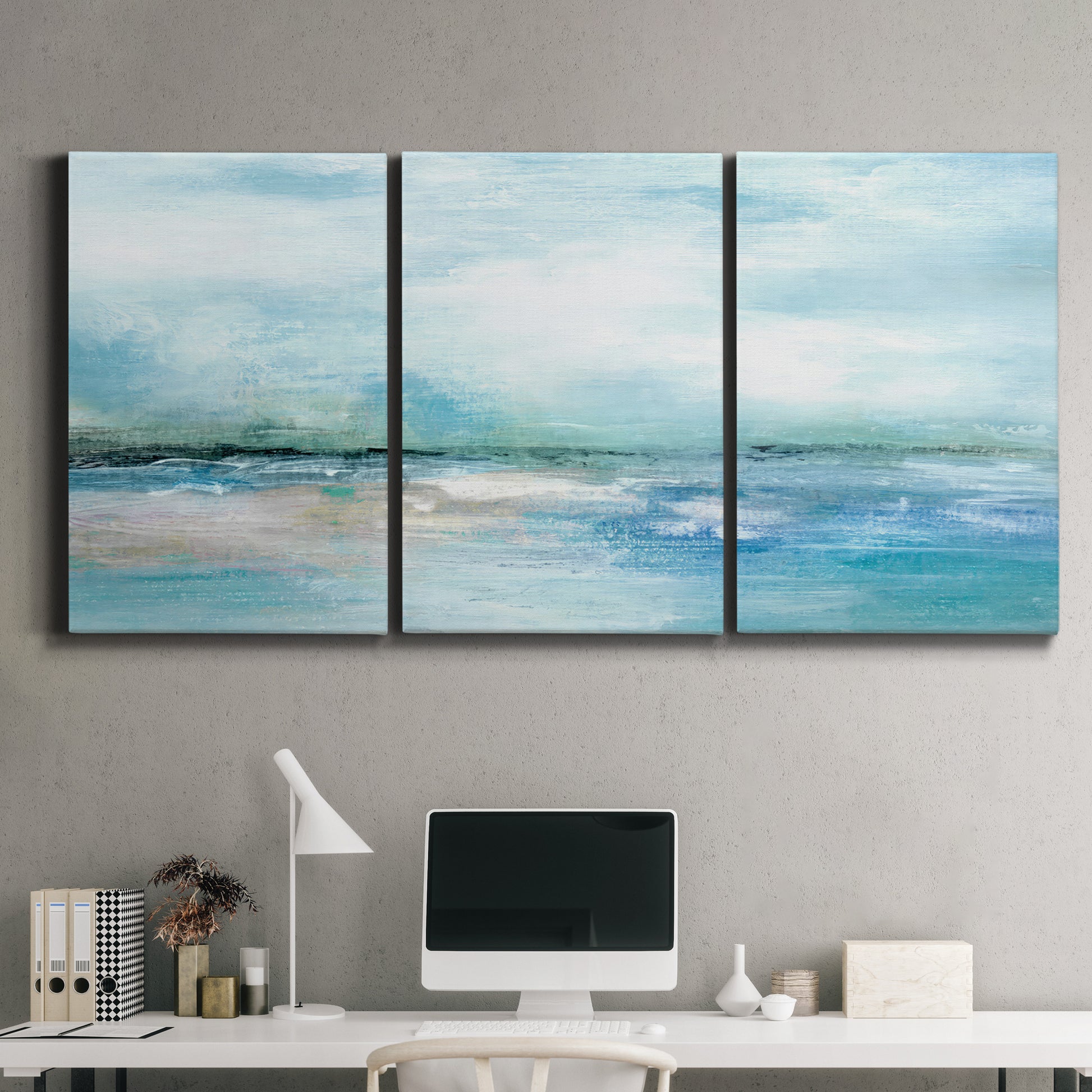 Three-panel canvas wall art featuring sunset silhouette over coastal water, displayed above a desk in a home office.