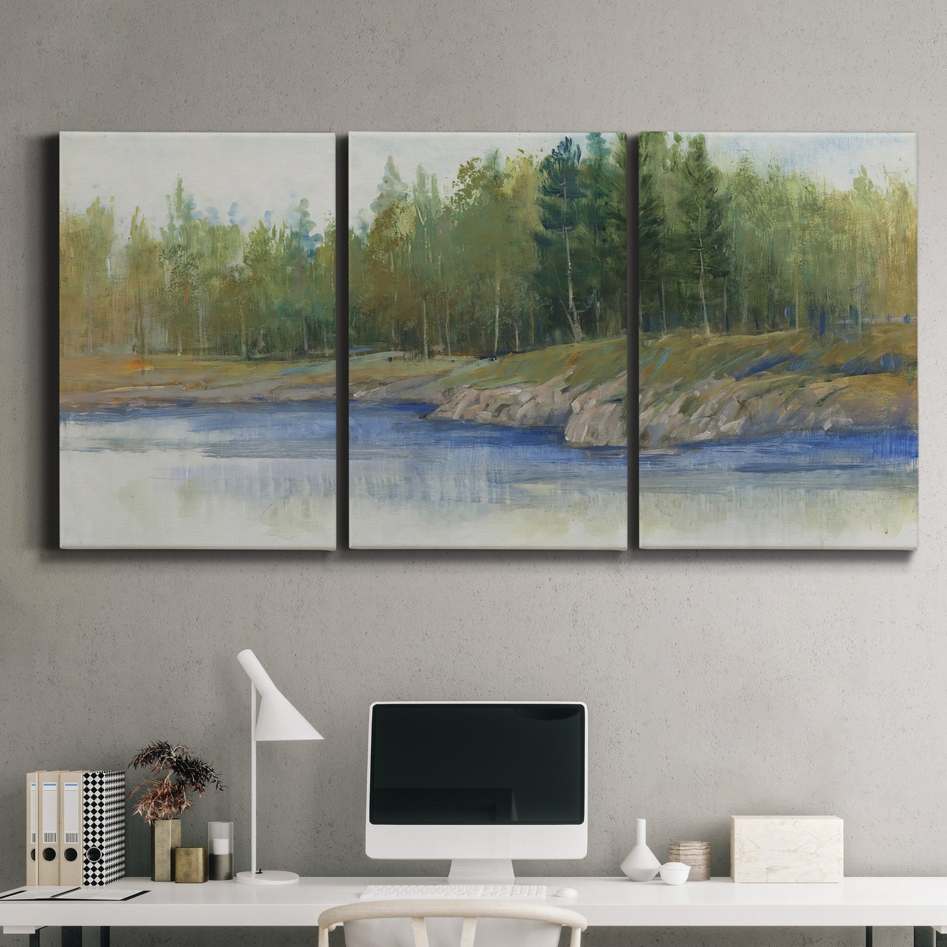 Three-panel canvas wall art featuring riverbank landscape with trees, displayed above a desk in a home office.