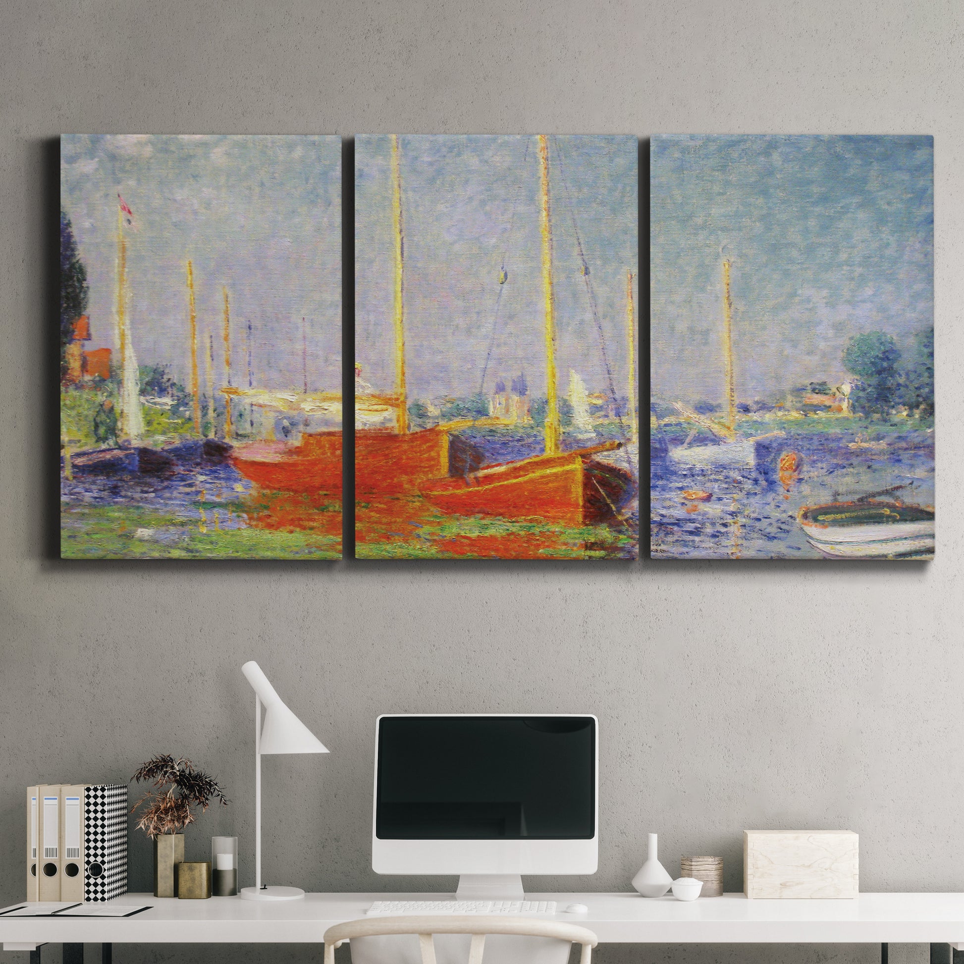 Three-panel canvas wall art featuring red boats along riverbank, displayed above a desk in a home office.