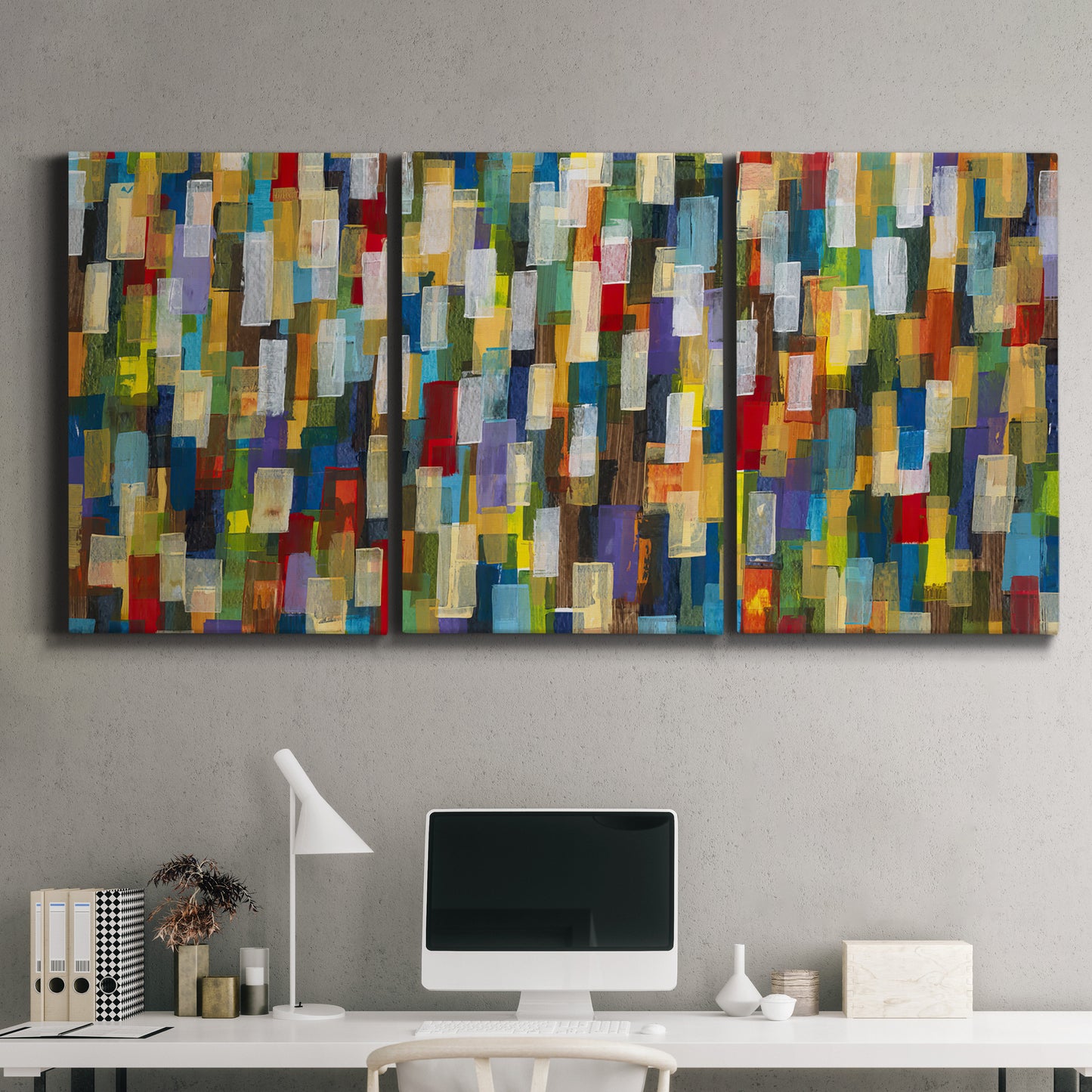 Three-panel canvas wall art featuring colorful confetti style abstraction, displayed above a desk in a home office.