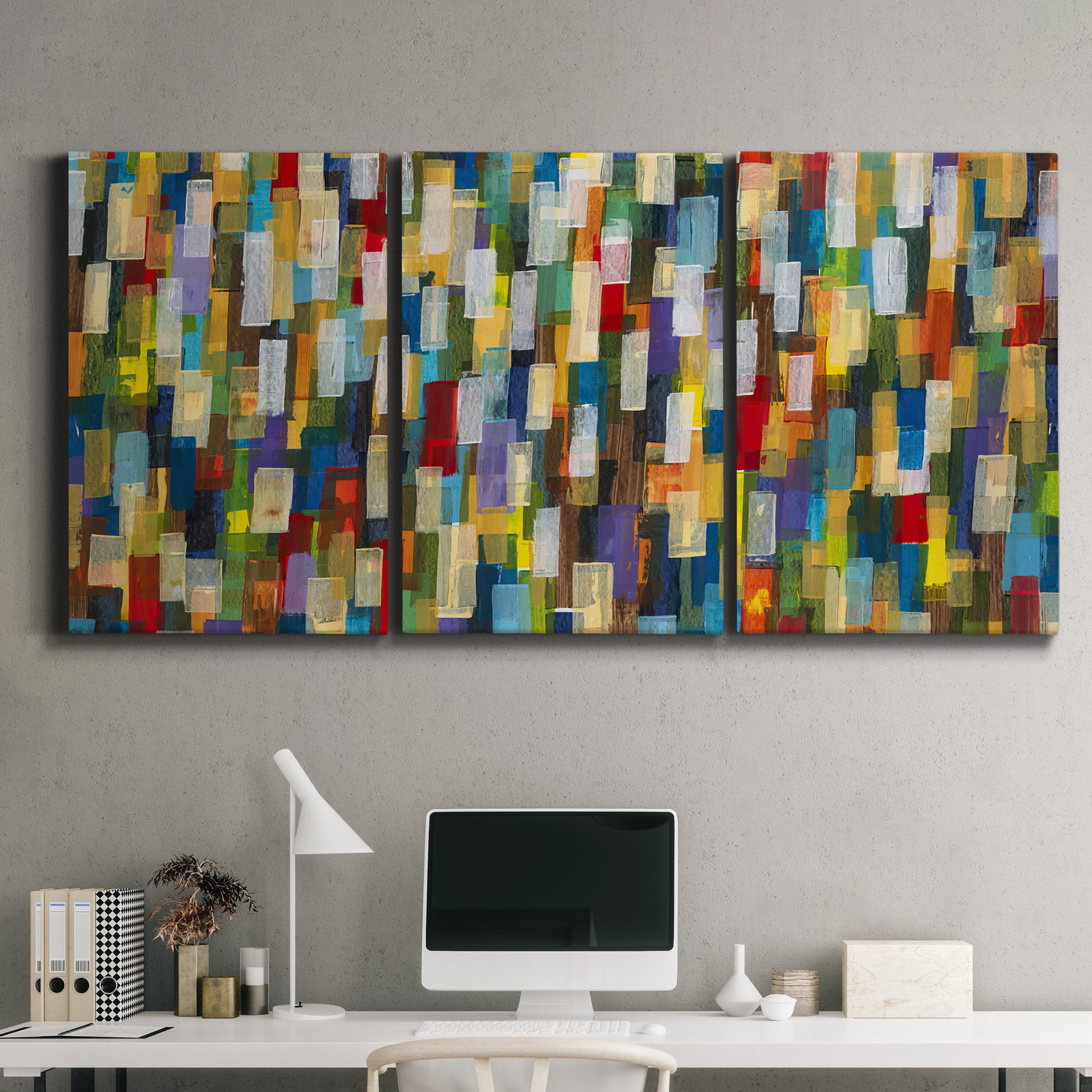 Three-panel canvas wall art featuring colorful confetti style abstraction, displayed above a desk in a home office.