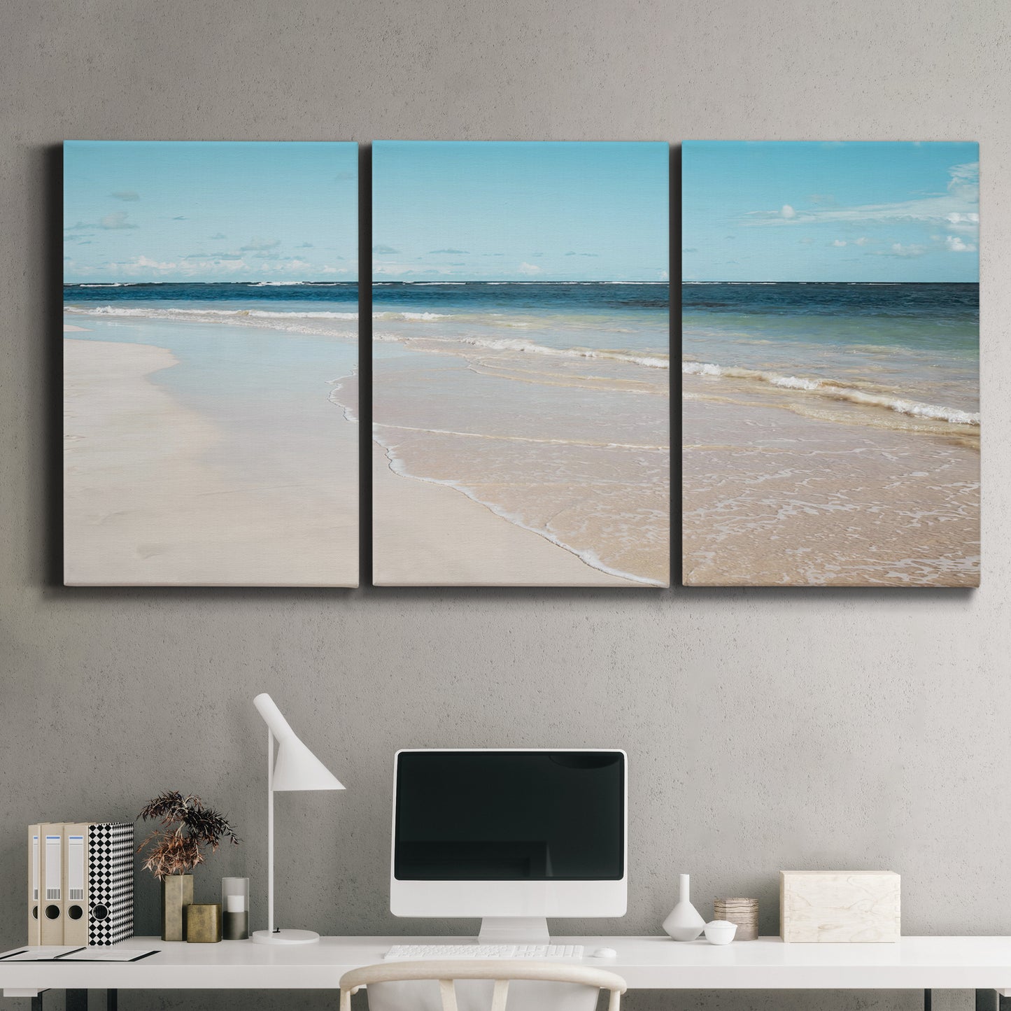 Three-panel canvas wall art featuring white sand beach with gentle waves, displayed above a desk in a home office.
