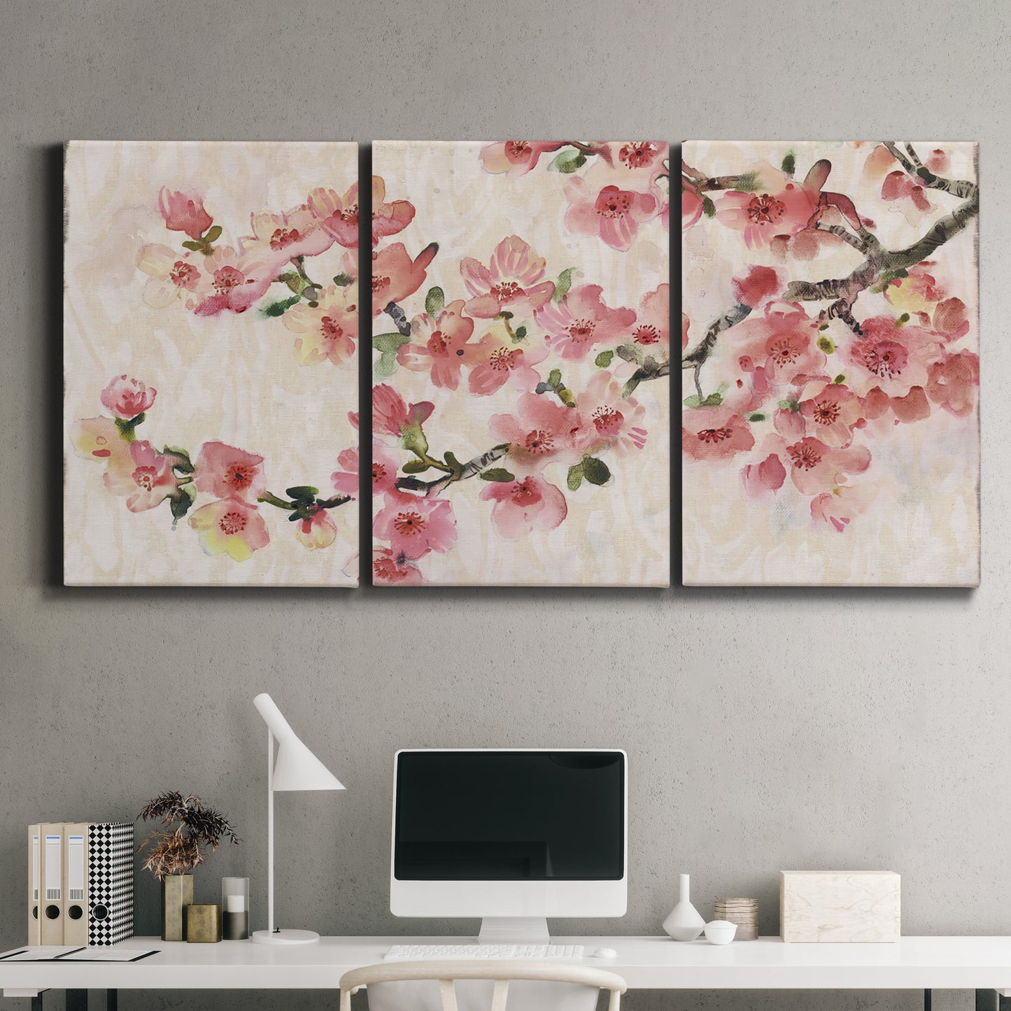 Three-panel canvas wall art featuring blooming cherry blossom branches, displayed above a desk in a home office.