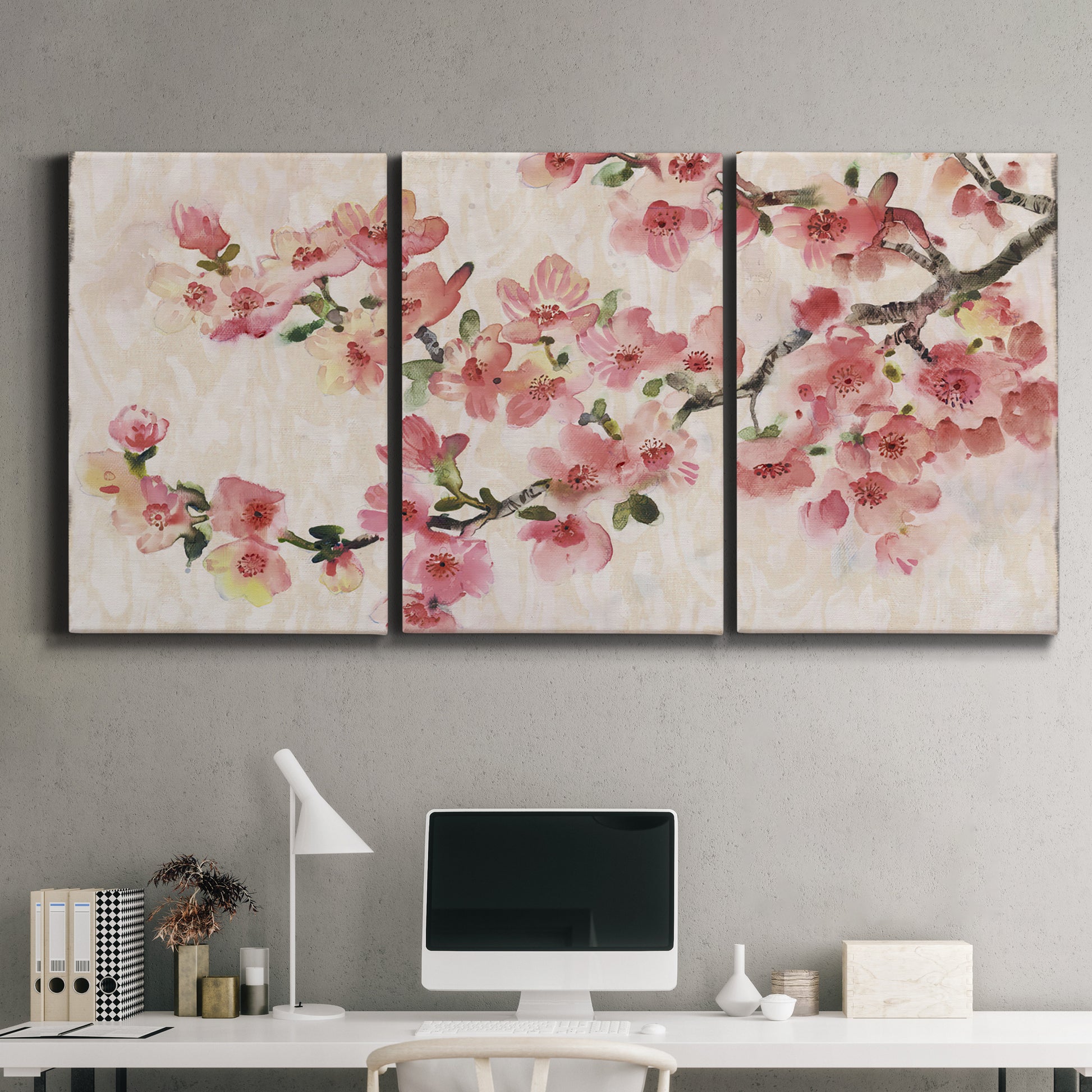 Three-panel canvas wall art featuring blooming cherry blossom branches, displayed above a desk in a home office.