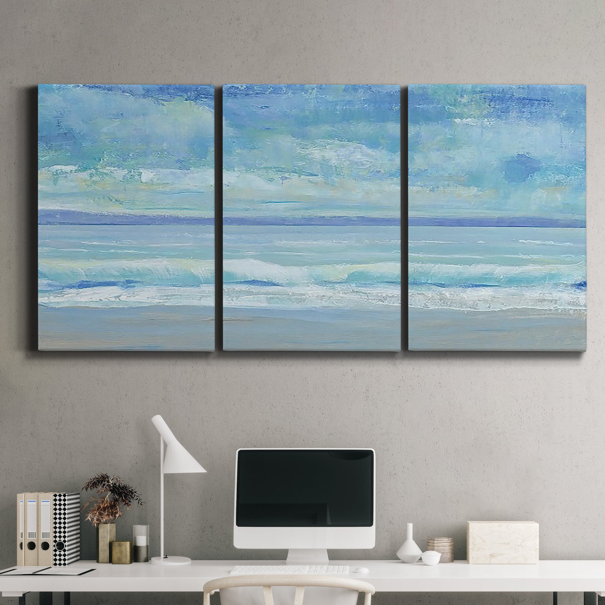 Three-panel canvas wall art featuring rolling ocean surf along shoreline, displayed above a desk in a home office.