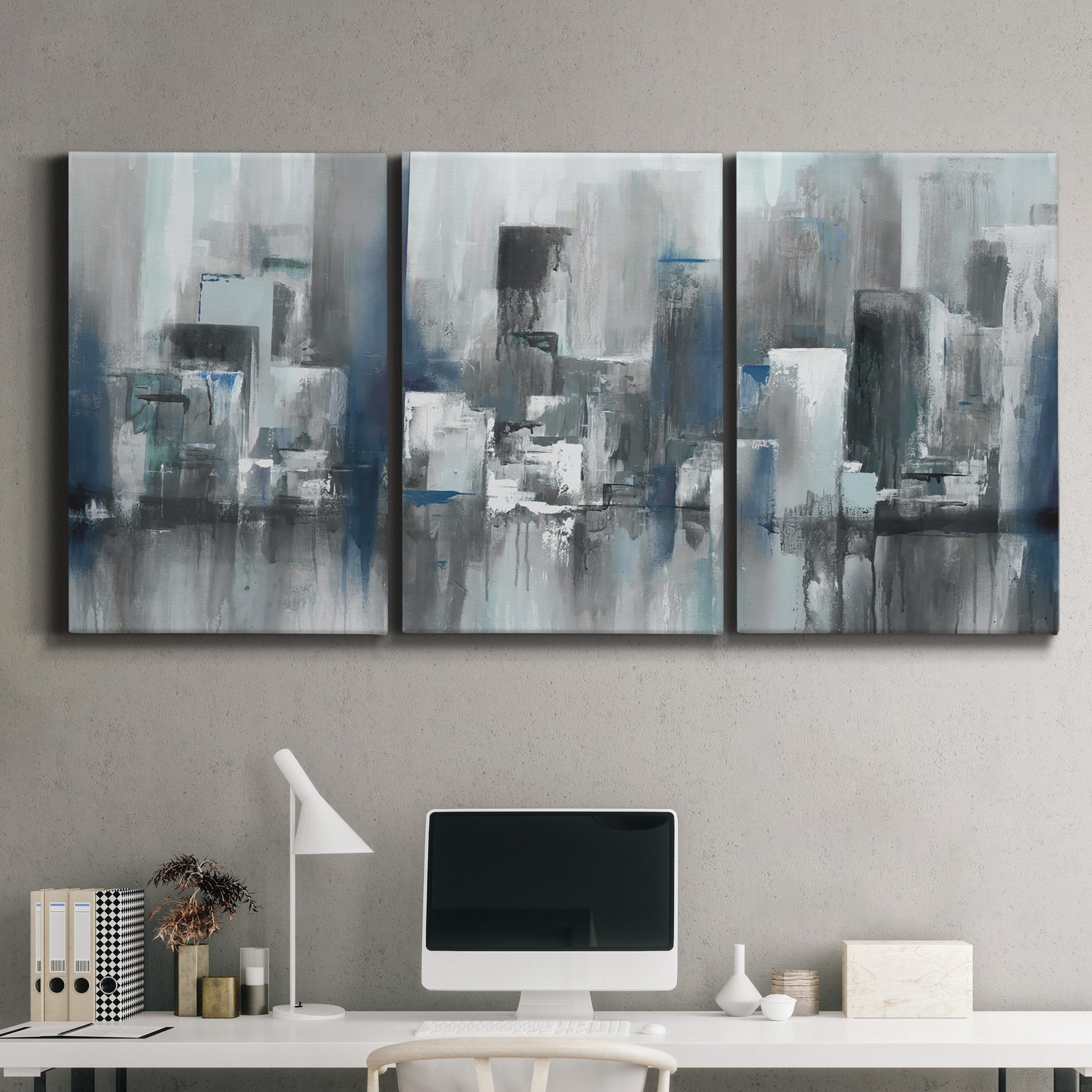 Three-panel canvas wall art featuring urban cityscape rendered in blue tones, displayed above a desk in a home office.