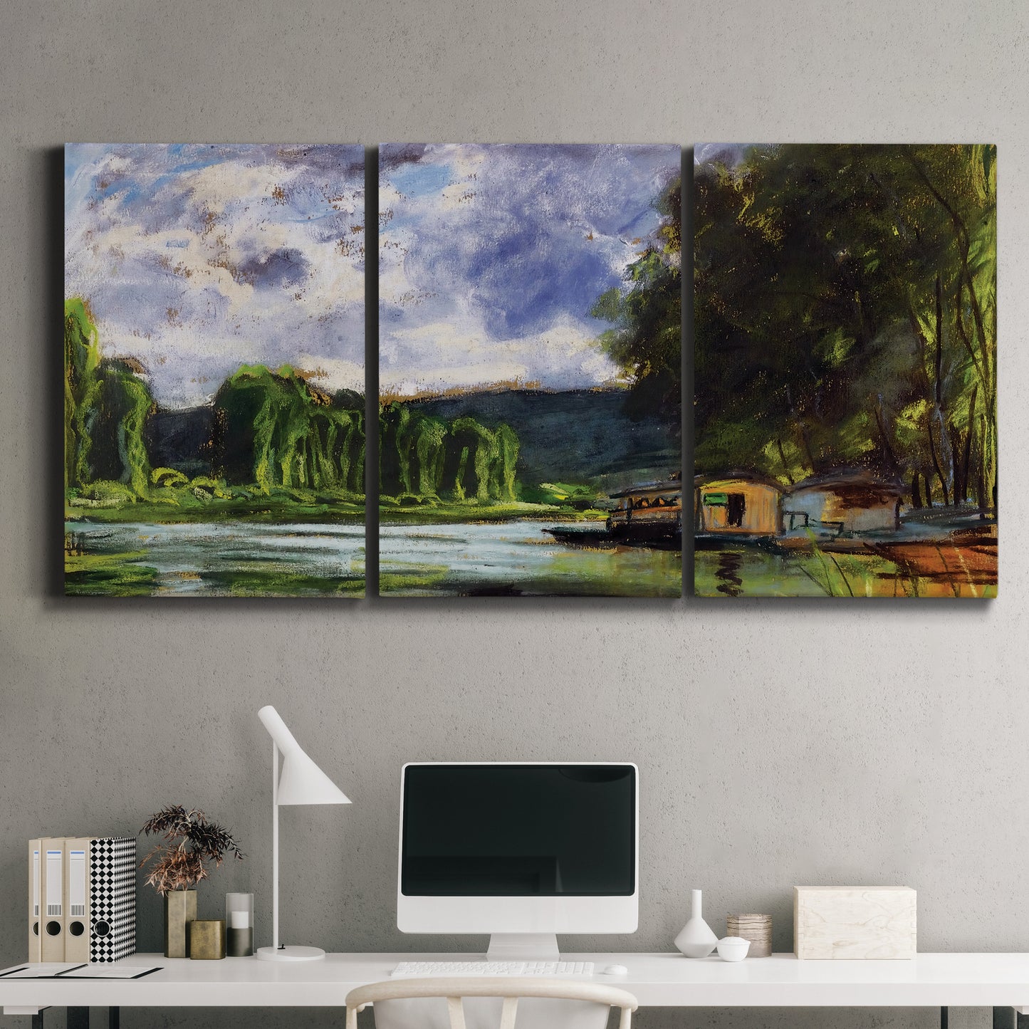 Three-panel canvas wall art featuring riverbank landscape near village, displayed above a desk in a home office.