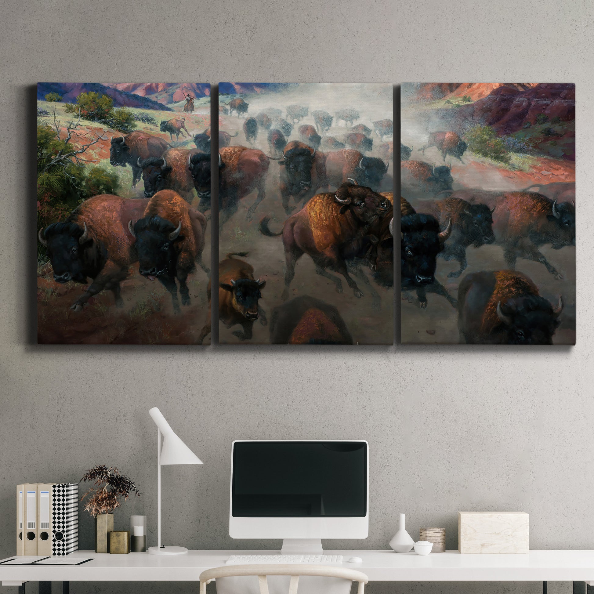 Three-panel canvas wall art featuring stormy canyon landscape with animals, displayed above a desk in a home office.