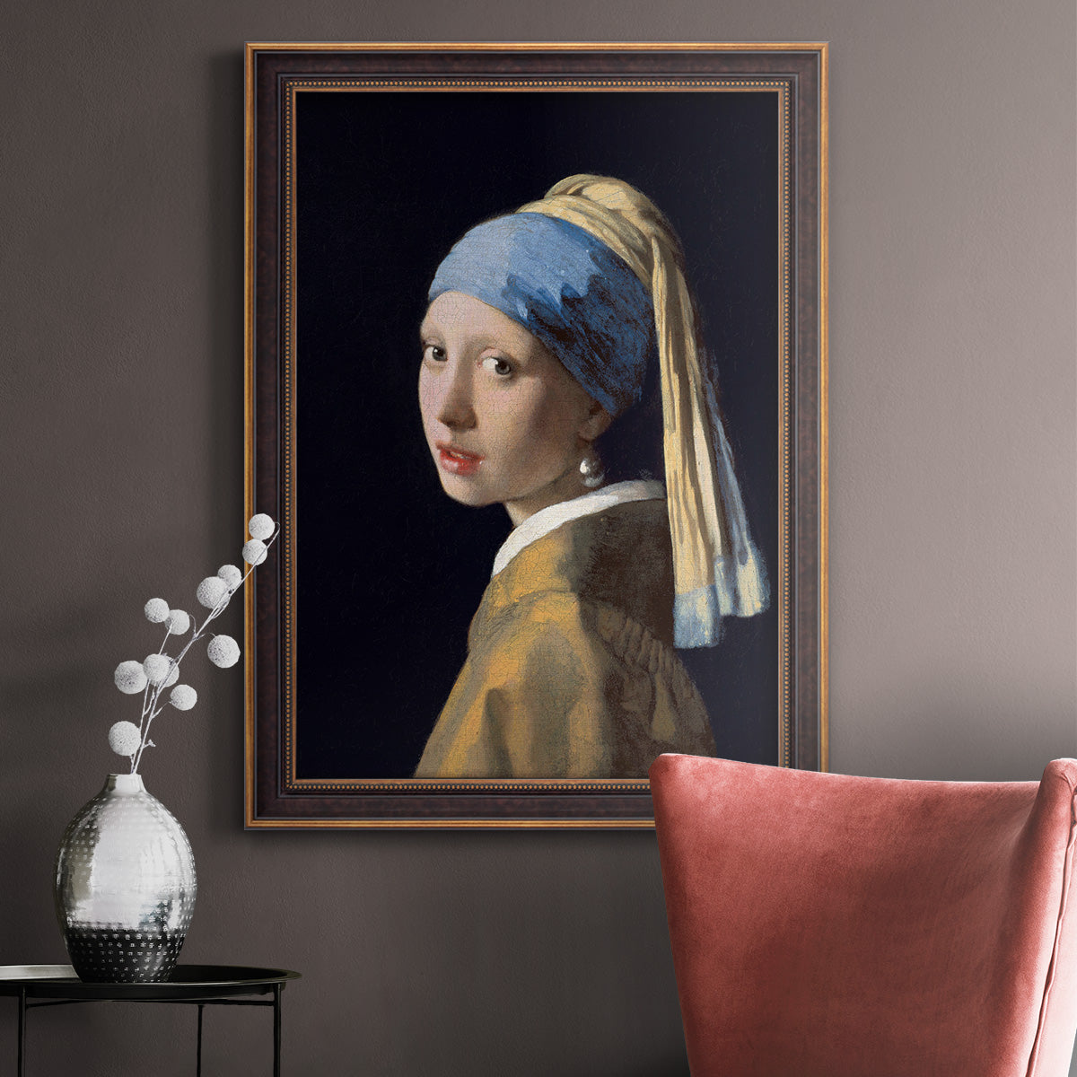 Iconic portrait of a girl wearing a pearl earring by Johannes Vermeer in an ornate bronzed mahogany wood frame displayed in a neutral interior setting.