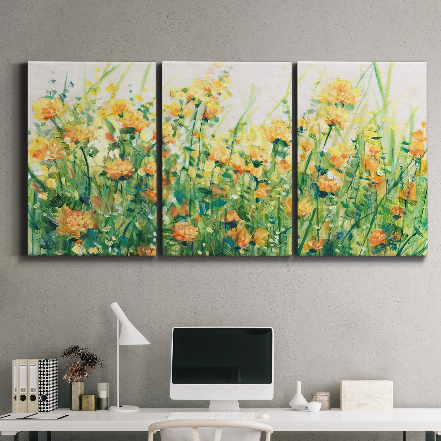 Three-panel canvas wall art featuring colorful garden flowers in bloom, displayed above a desk in a home office.