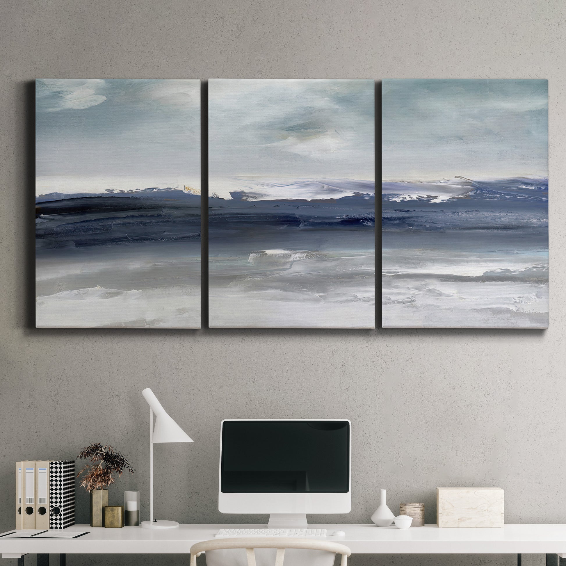 Three-panel canvas wall art featuring abstract coastal tones and movement, displayed above a desk in a home office.