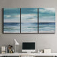 Three-panel canvas wall art featuring calm coastal shoreline, displayed above a desk in a home office.