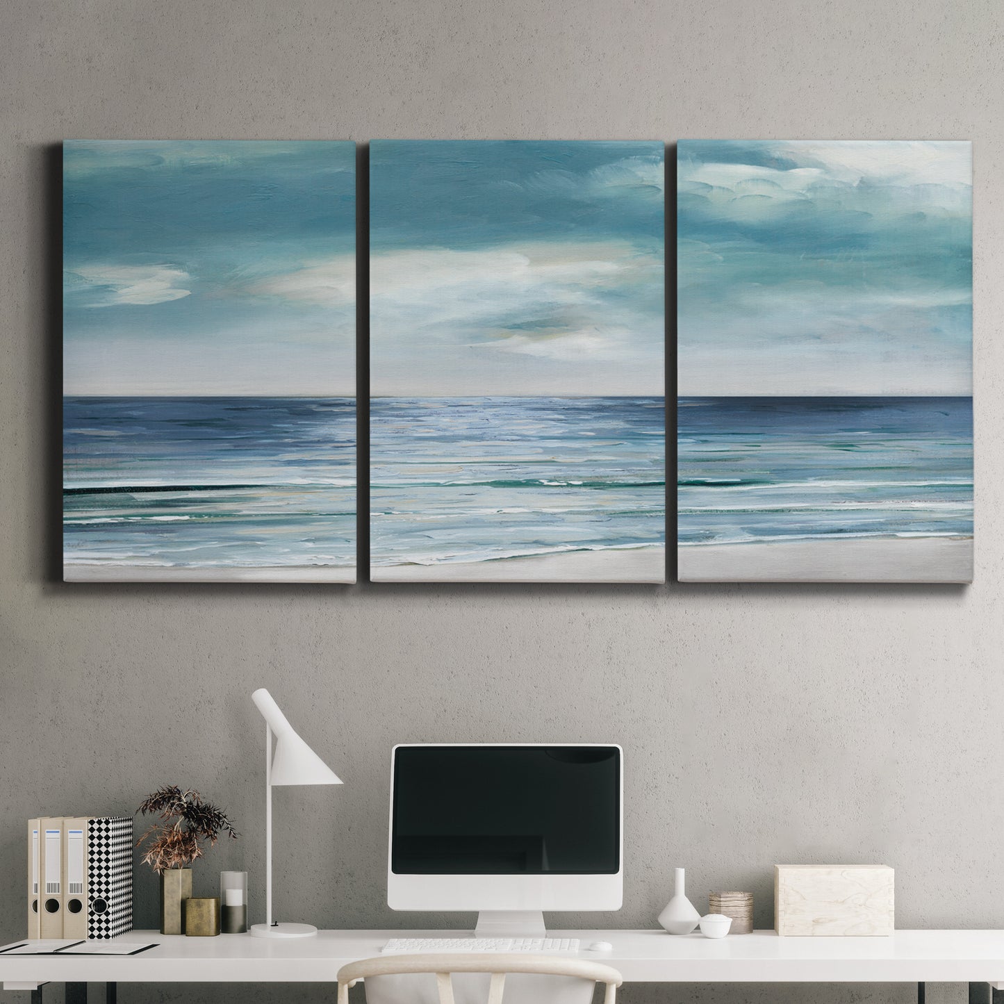 Three-panel canvas wall art featuring calm coastal shoreline, displayed above a desk in a home office.