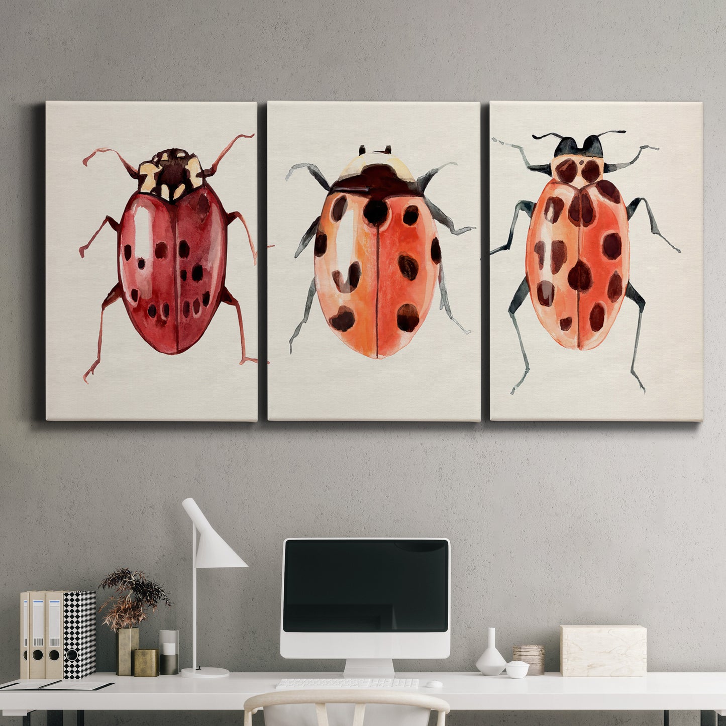 Three-panel canvas wall art featuring ladybugs on green foliage, displayed above a desk in a home office.
