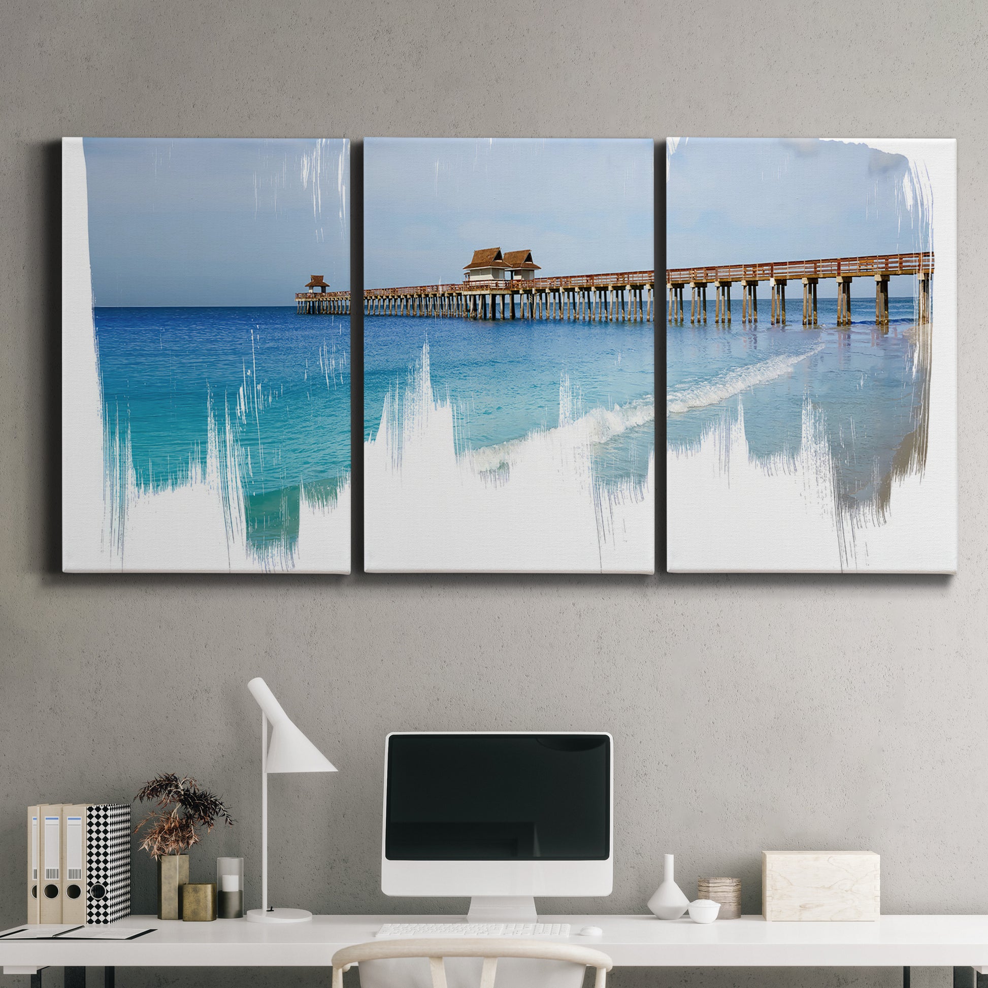 Three-panel canvas wall art featuring coastal pier extending over water, displayed above a desk in a home office.