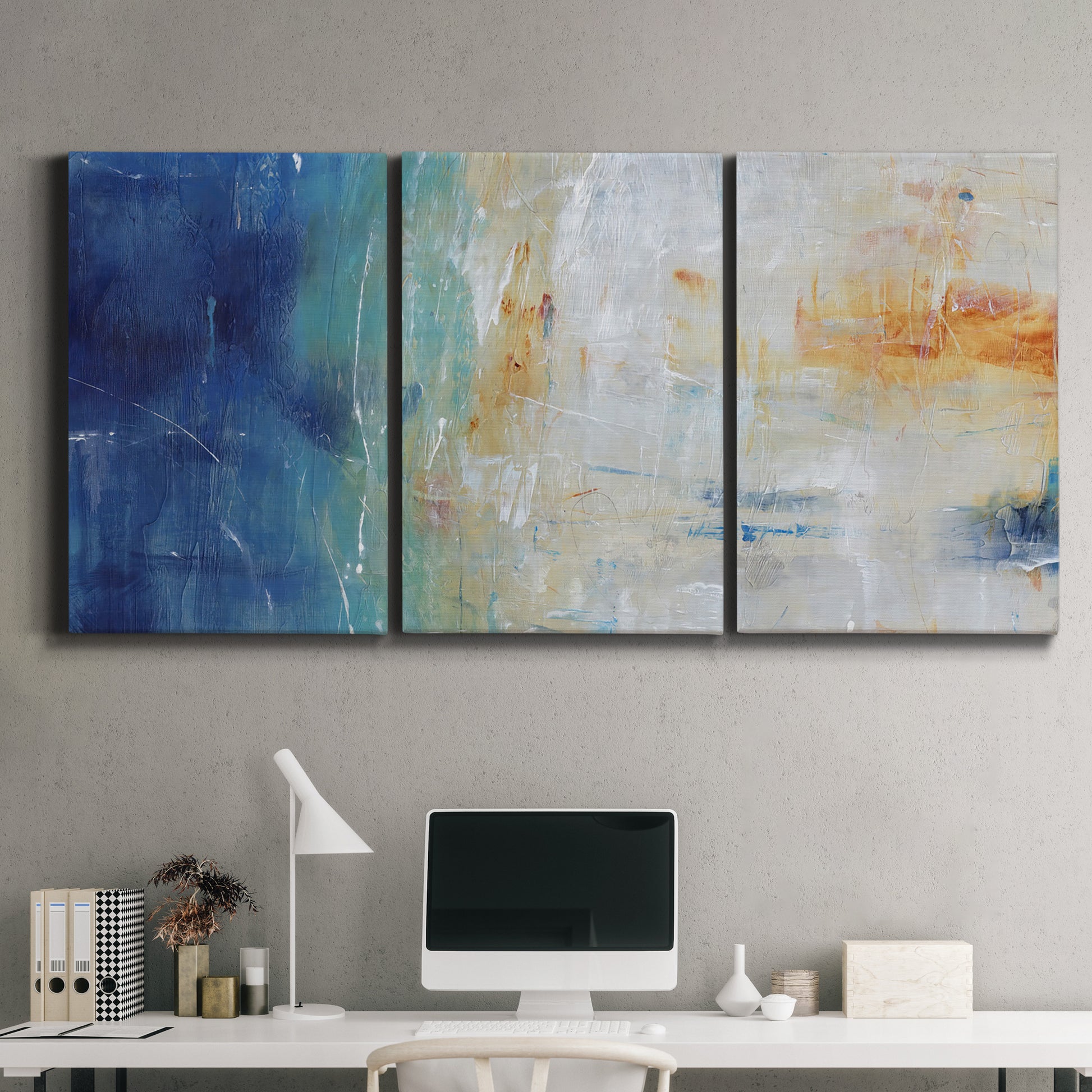 Three-panel canvas wall art featuring deep blue abstract grotto tones, displayed above a desk in a home office.