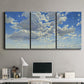 Three-panel canvas wall art featuring whimsical cloud filled sky landscape, displayed above a desk in a home office.
