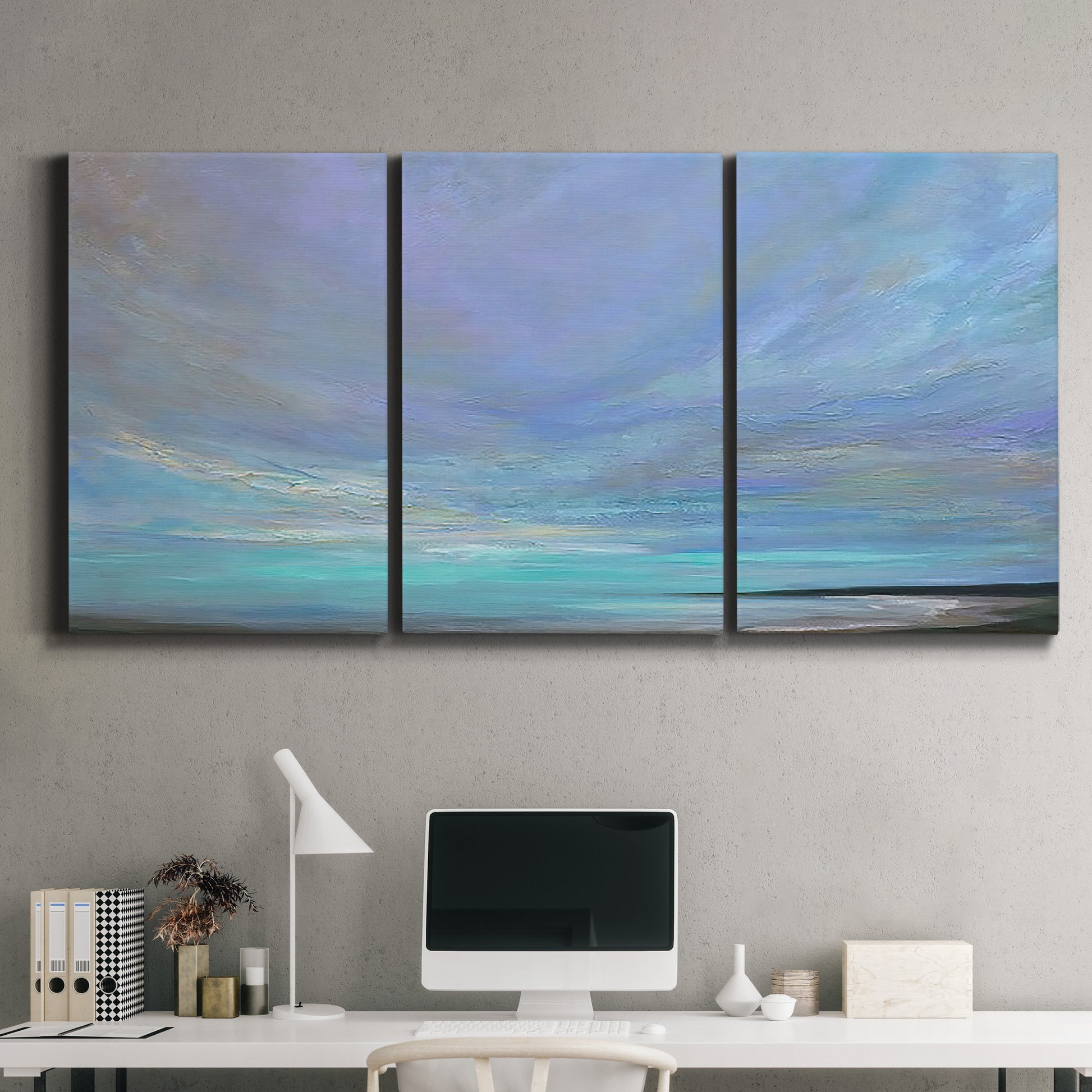 Three-panel canvas wall art featuring coastal shoreline with gentle surf, displayed above a desk in a home office.