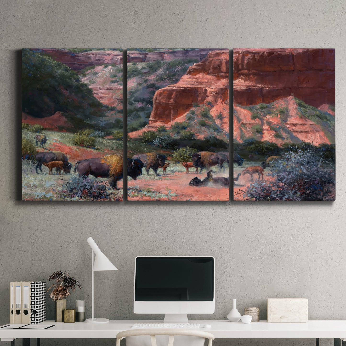 Three-panel canvas wall art featuring rugged canyon landscape with wildlife, displayed above a desk in a home office.
