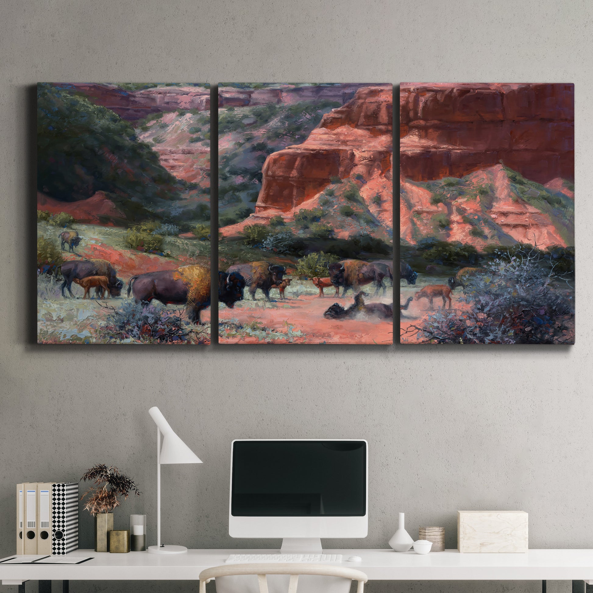 Three-panel canvas wall art featuring rugged canyon landscape with wildlife, displayed above a desk in a home office.