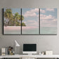 Three-panel canvas wall art featuring tropical sand dunes with palms, displayed above a desk in a home office.