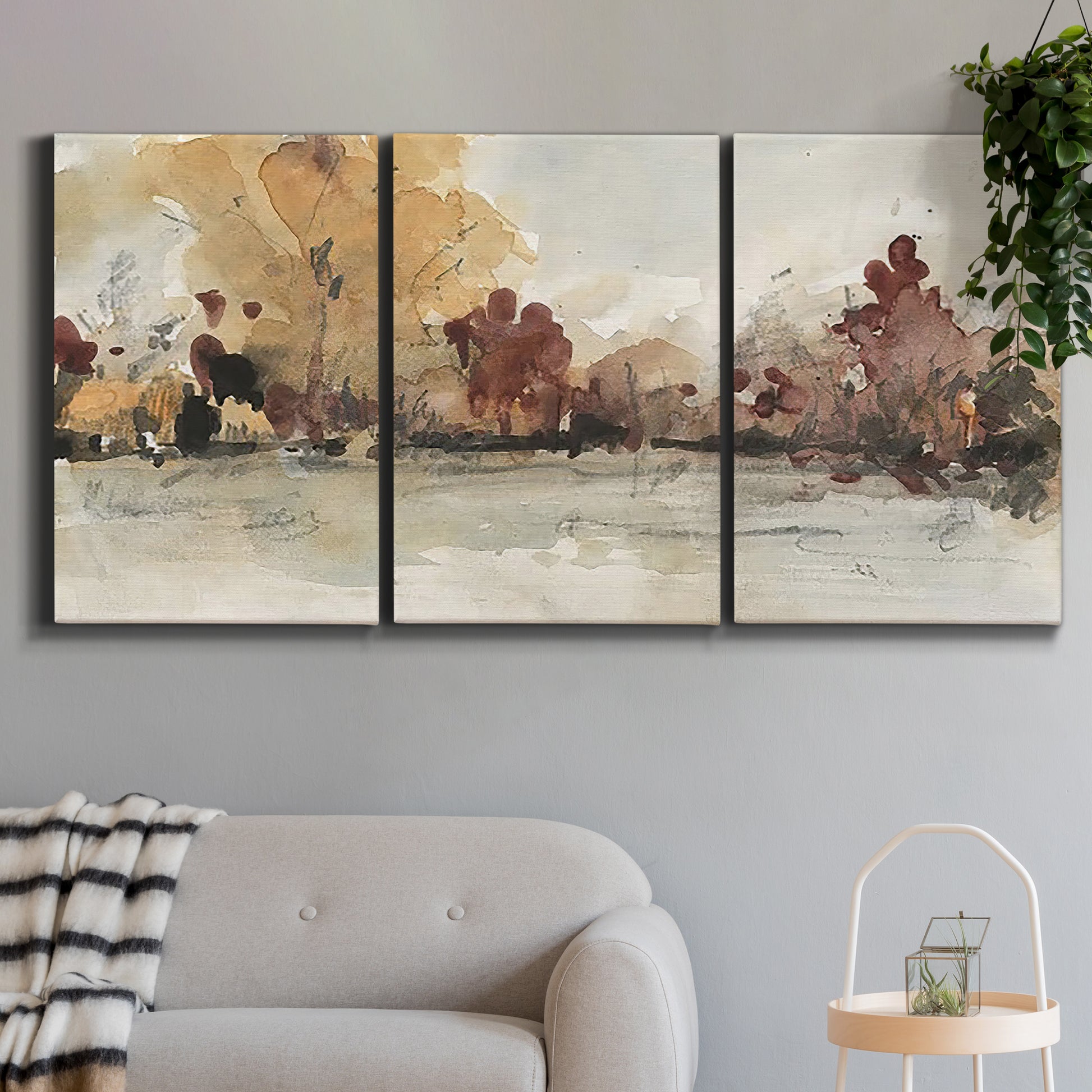 Three-panel canvas wall art featuring autumn landscape with trees and field, displayed in a modern living room above a sofa.