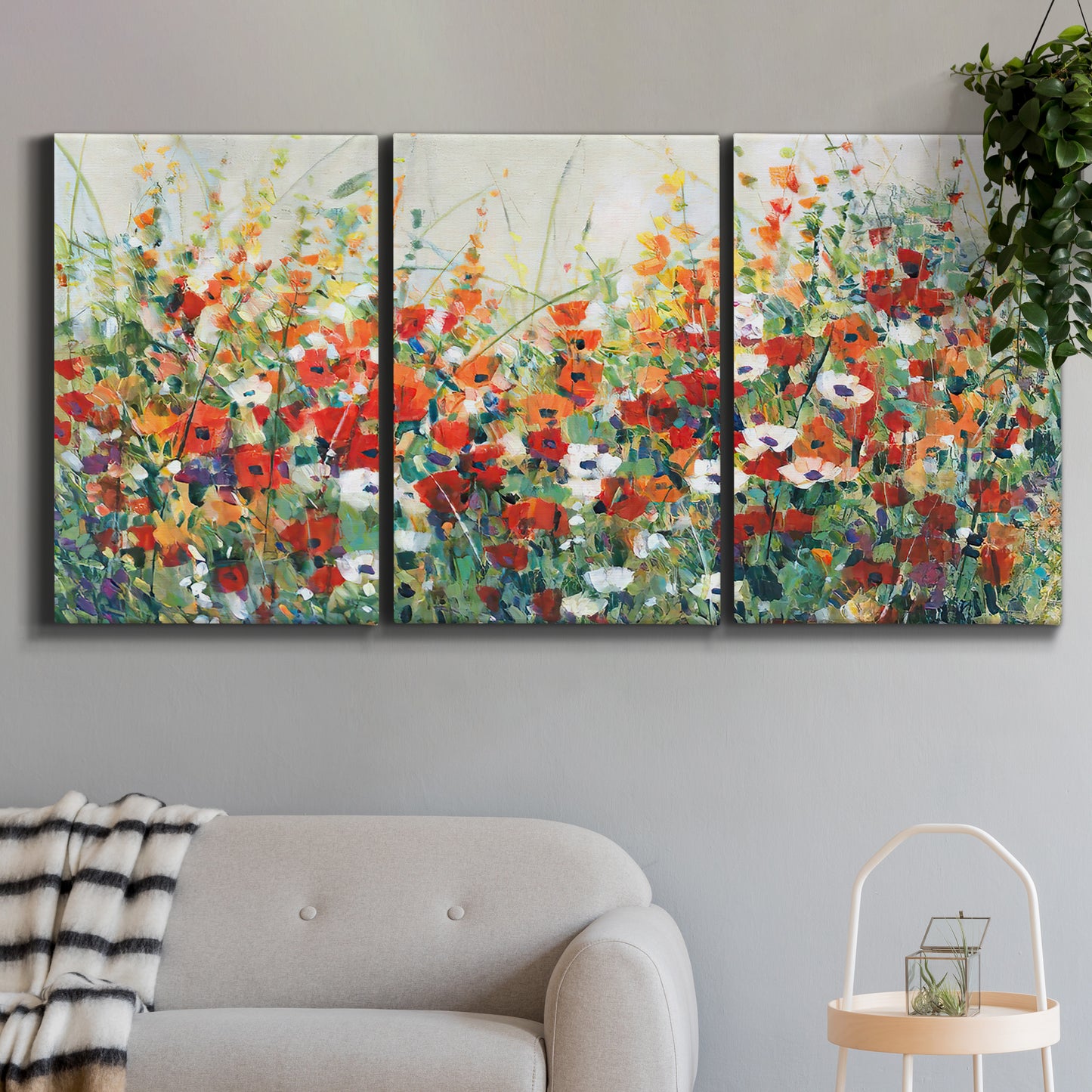 Three-panel canvas wall art featuring colorful garden flowers in bloom, displayed in a modern living room above a sofa.
