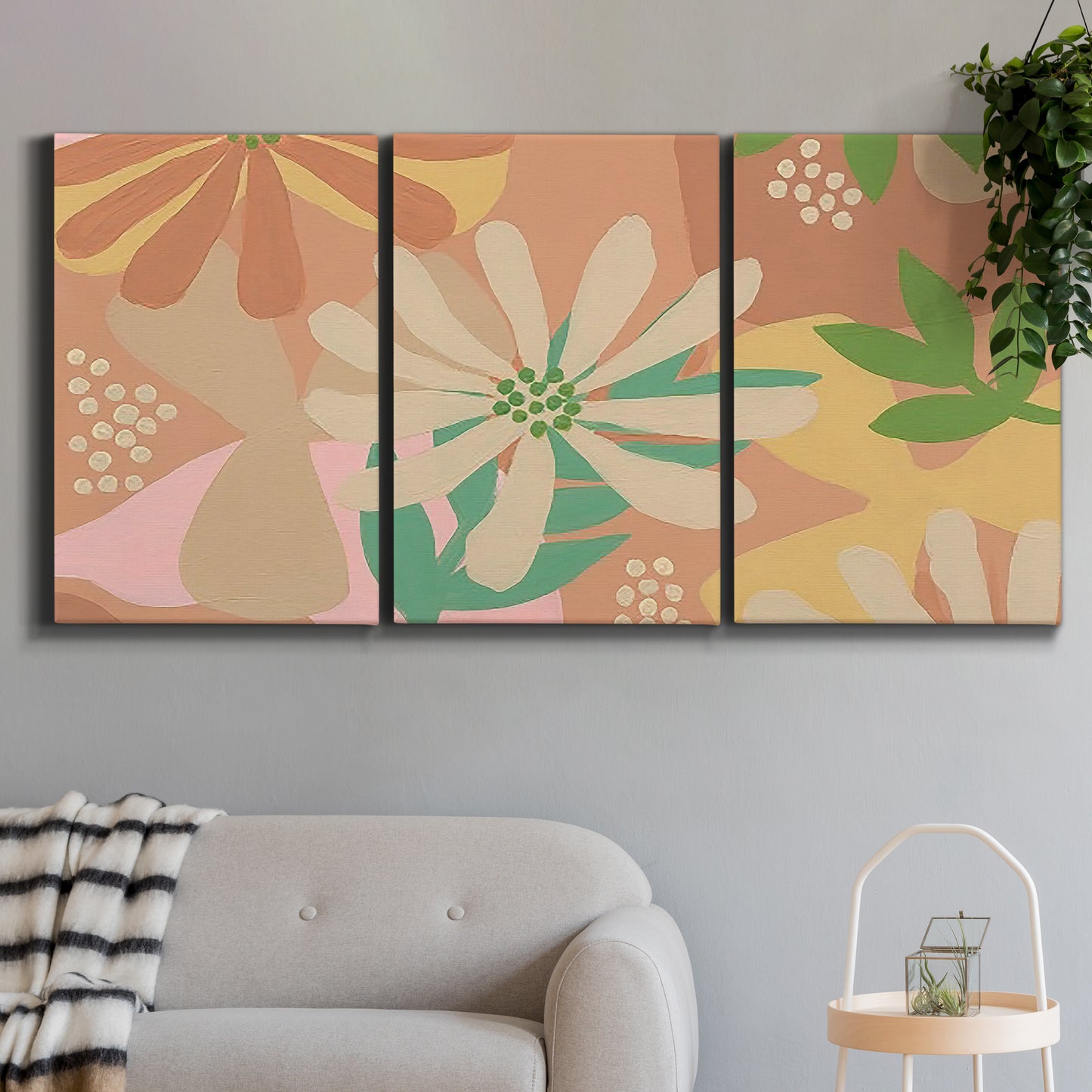 Three-panel canvas wall art featuring neutral toned botanical floral silhouettes, displayed in a modern living room above a sofa.