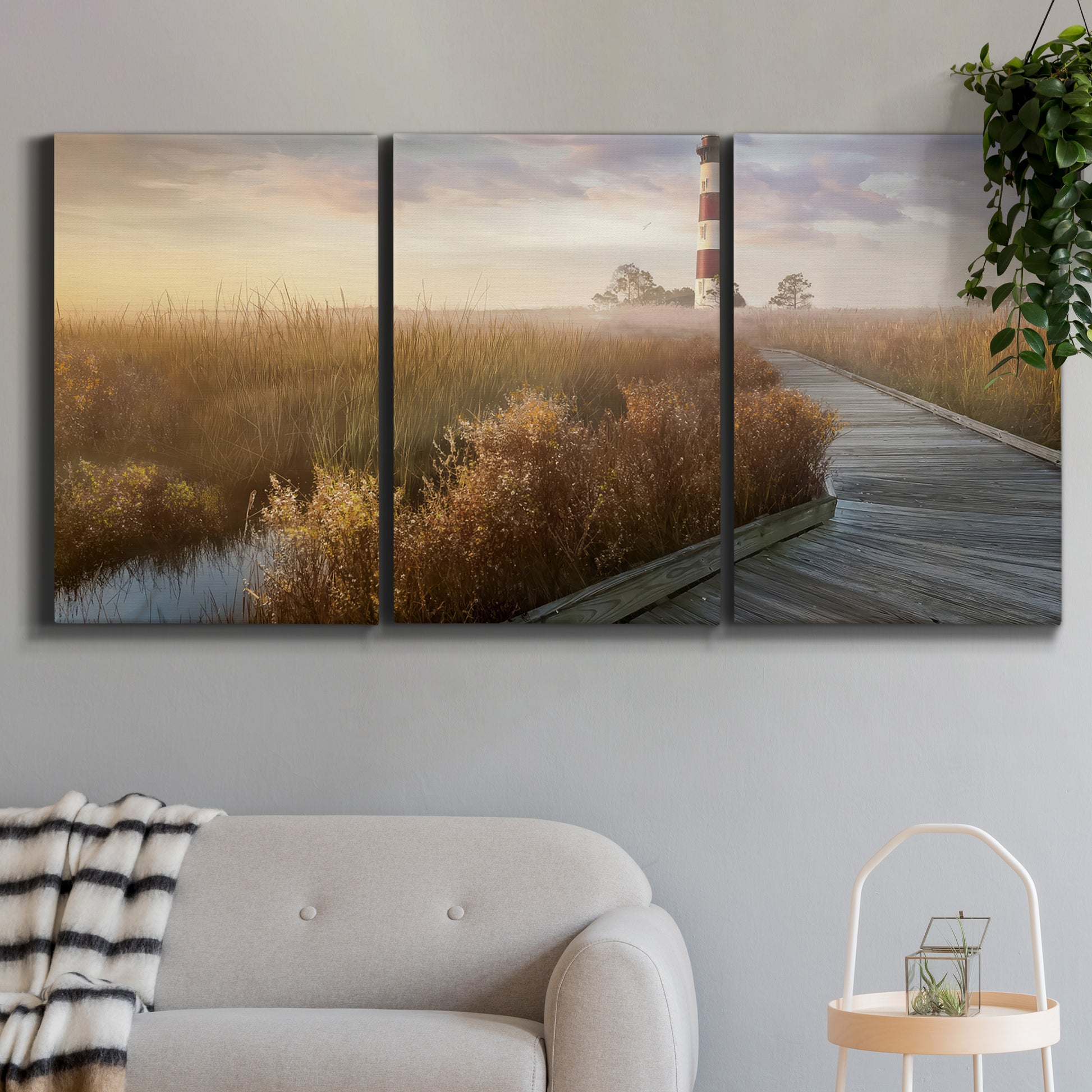 Three-panel canvas wall art featuring coastal path leading to shore, displayed in a modern living room above a sofa.