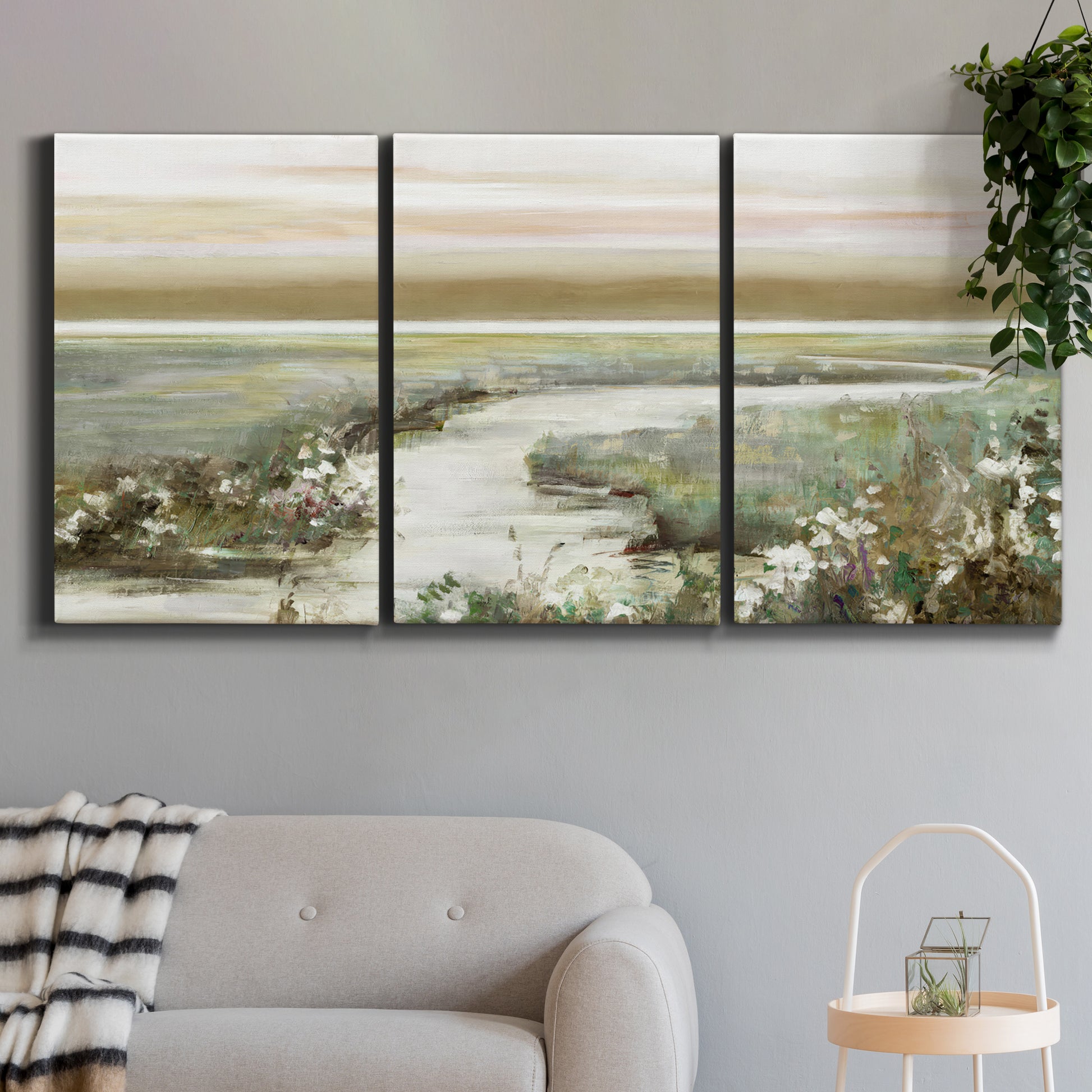 Three-panel canvas wall art featuring pastoral fields under soft sunrise, displayed in a modern living room above a sofa.