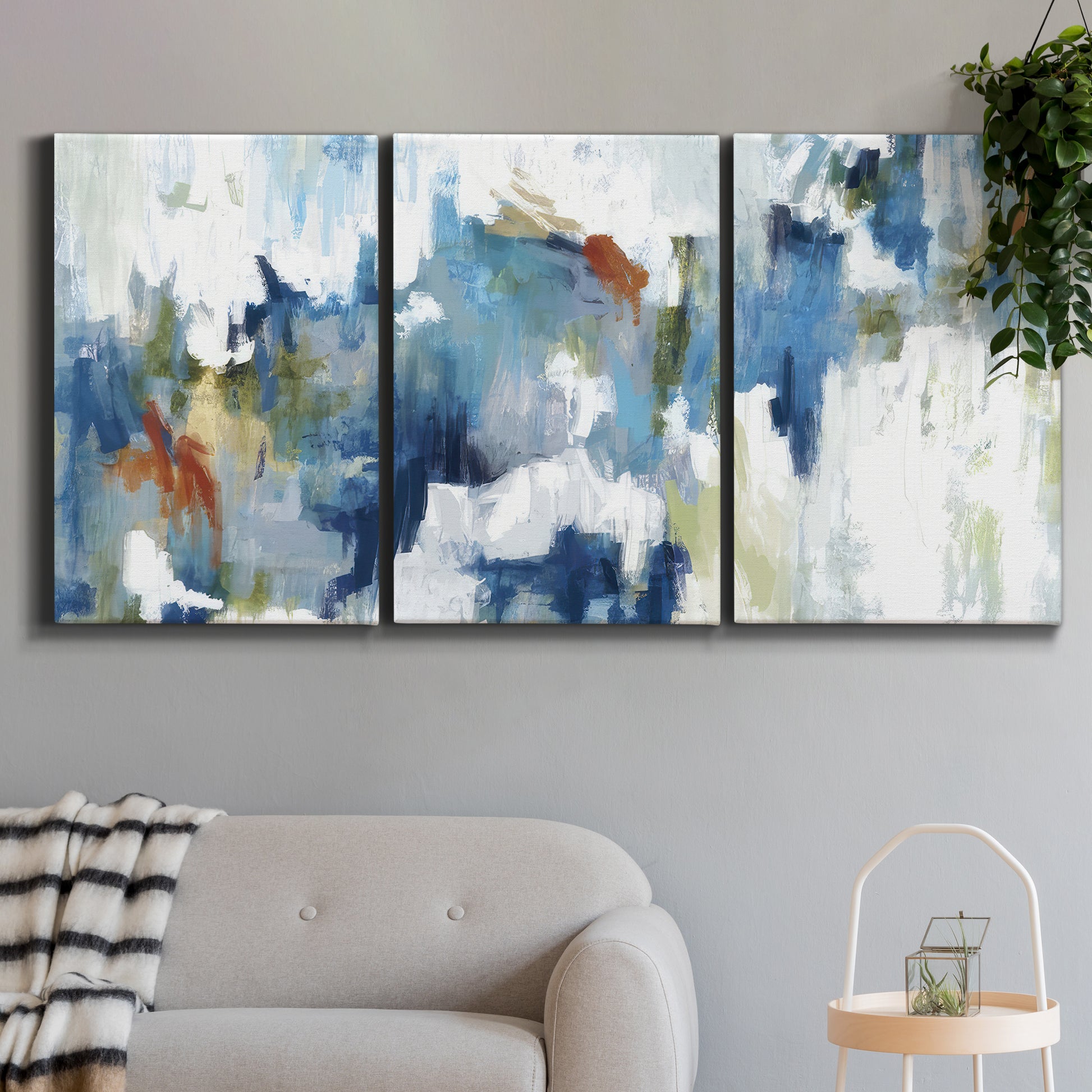 Three-panel canvas wall art featuring flowing abstract color movement, displayed in a modern living room above a sofa.