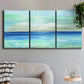 Three-panel canvas wall art featuring vast open blue ocean horizon, displayed in a modern living room above a sofa.