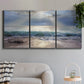 Three-panel canvas wall art featuring soft sunrise over open water, displayed in a modern living room above a sofa.