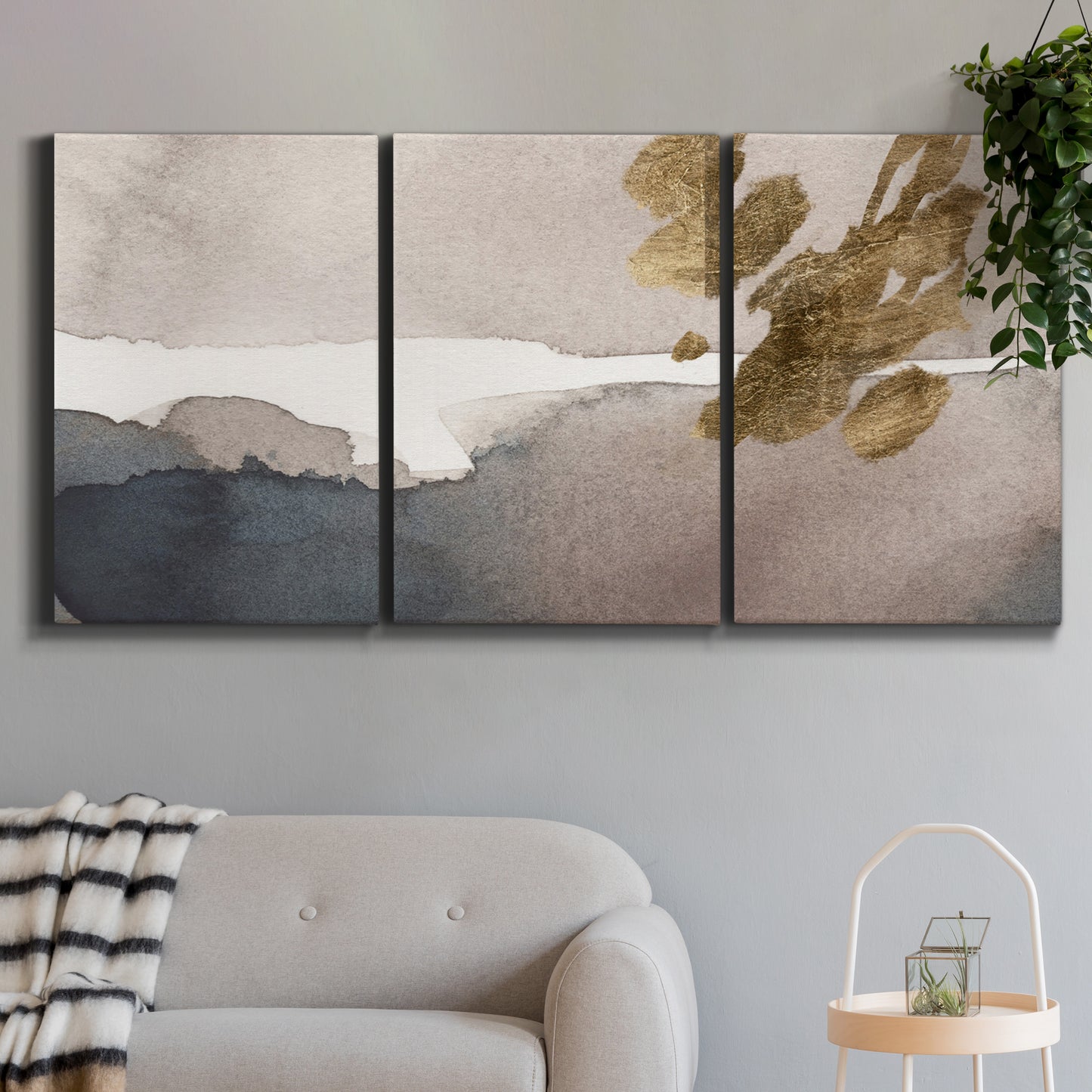 Three-panel canvas wall art featuring abstract watercolor with gold accents, displayed in a modern living room above a sofa.