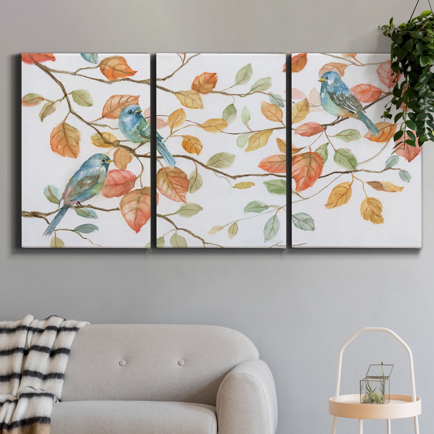 Three-panel canvas wall art featuring decorative bird trio illustration, displayed in a modern living room above a sofa.