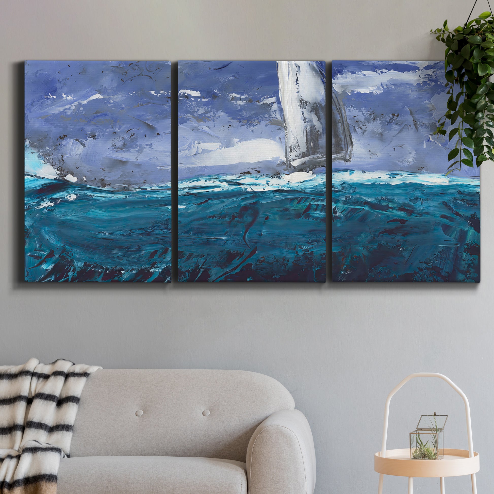 Three-panel canvas wall art featuring sailboats moving across water, displayed in a modern living room above a sofa.