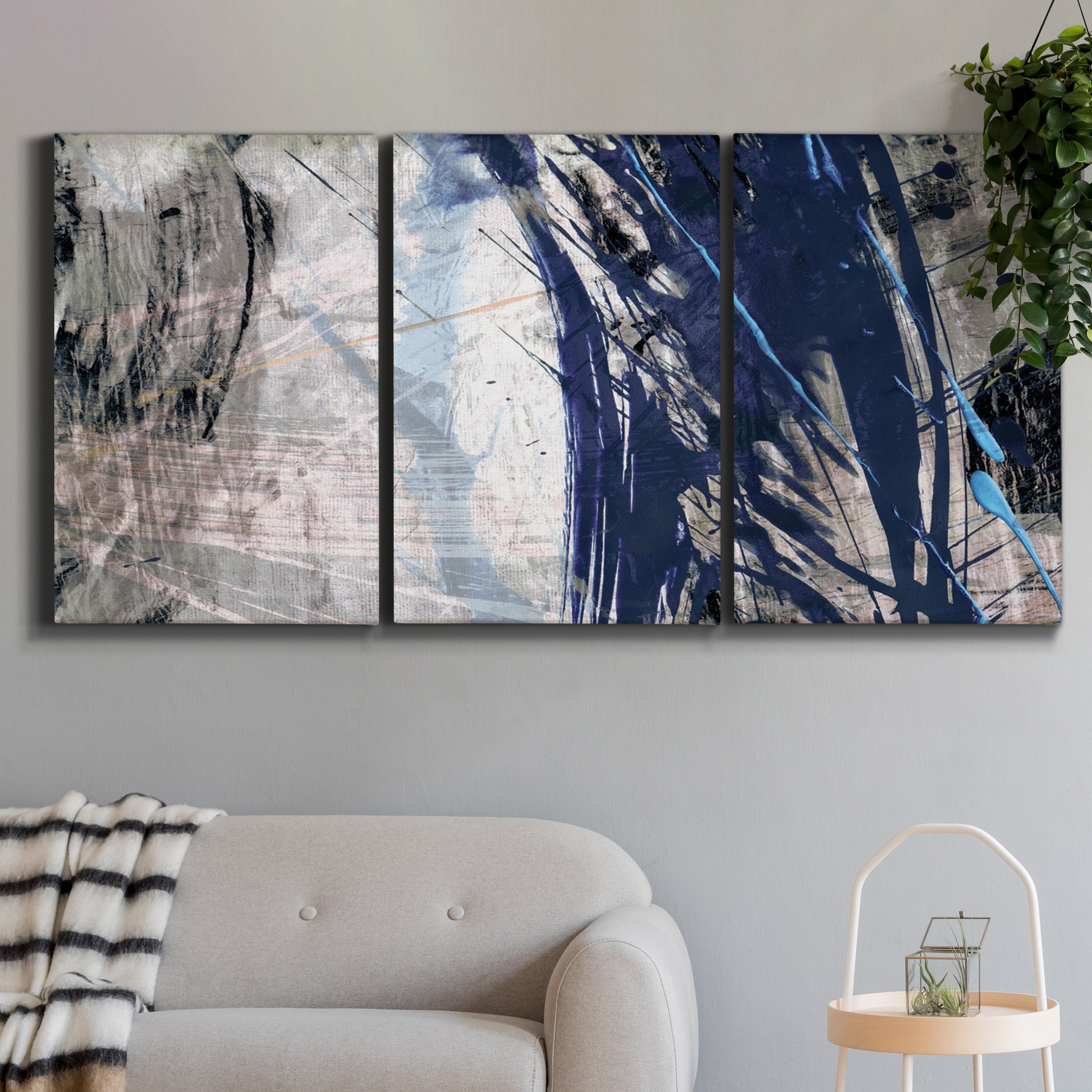 Three-panel canvas wall art featuring layered blue abstract texture, displayed in a modern living room above a sofa.