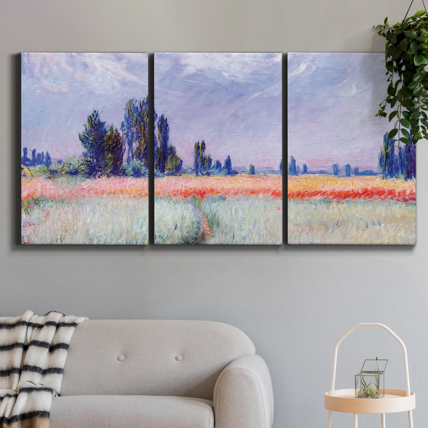 Three-panel canvas wall art featuring flowering field with poppies, displayed in a modern living room above a sofa.